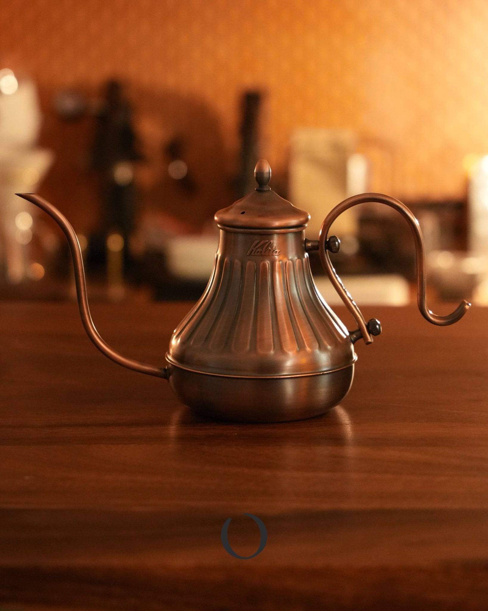 Kalita copper pour-over kettle with elegant design, long curved spout for precise pouring, and 900ml capacity, ideal for coffee enthusiasts, displayed on wooden surface in warm lighting