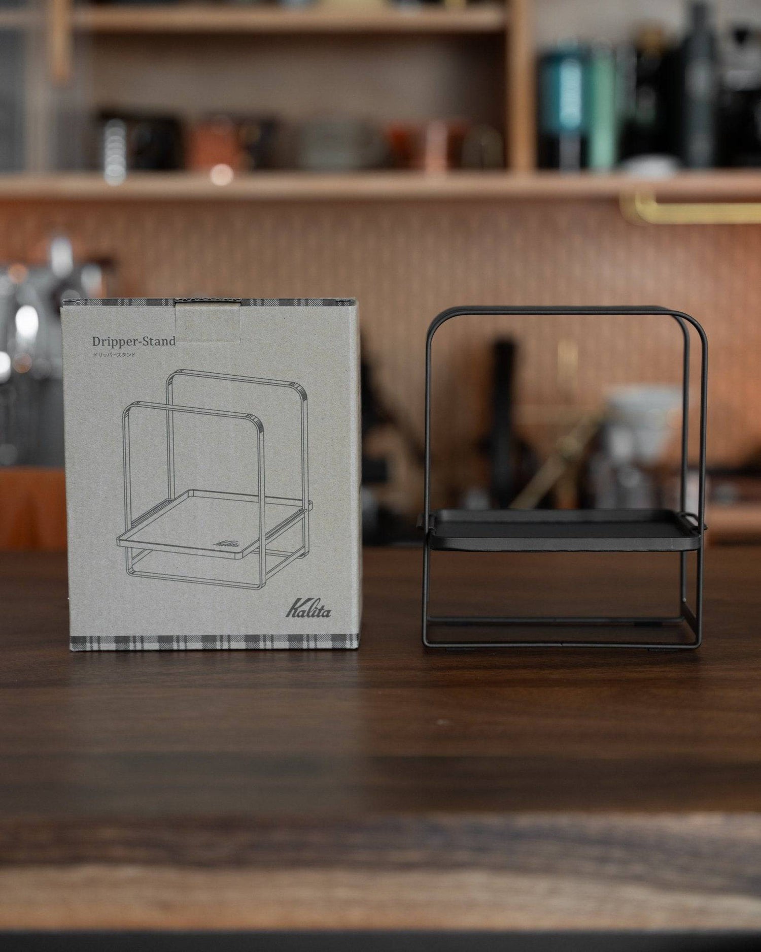 Kalita adjustable coffee dripper stand on wooden surface with product box, showcasing sleek black metal design and versatile functionality in kitchen setting