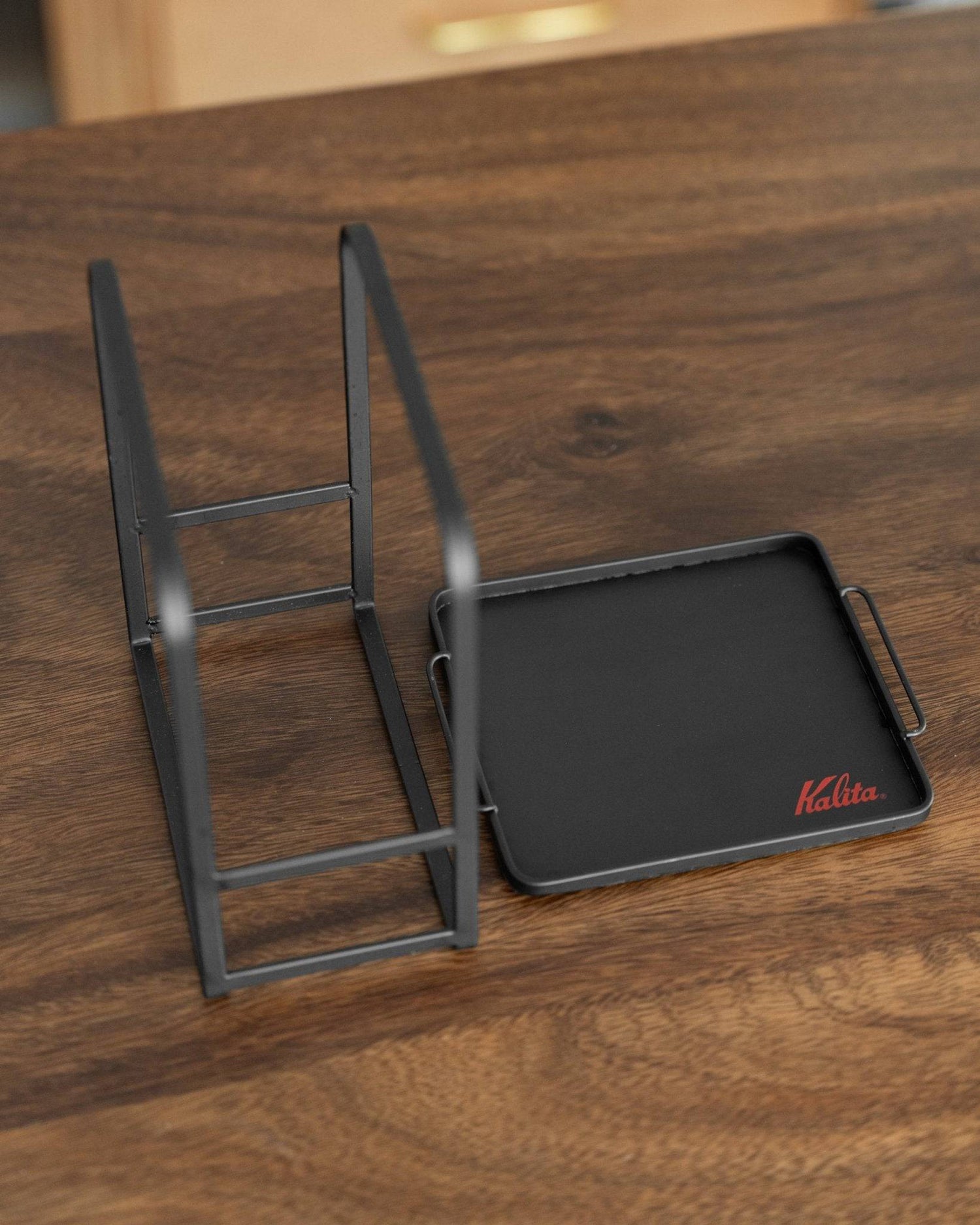 Kalita adjustable coffee dripper stand with black tray on wooden surface, showcasing its sleek design and versatility for pour-over brewing