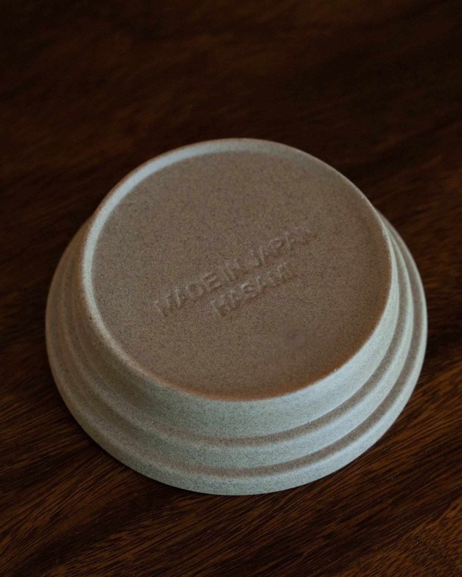 Kalita & HASAMI sandstone coffee dripper tray, showcasing Hasami-yaki craftsmanship. Circular design with raised center ring, textured matte finish. Made in Japan, suitable for various Kalita wave dripper models. Unique blend of traditional technique and modern style.
