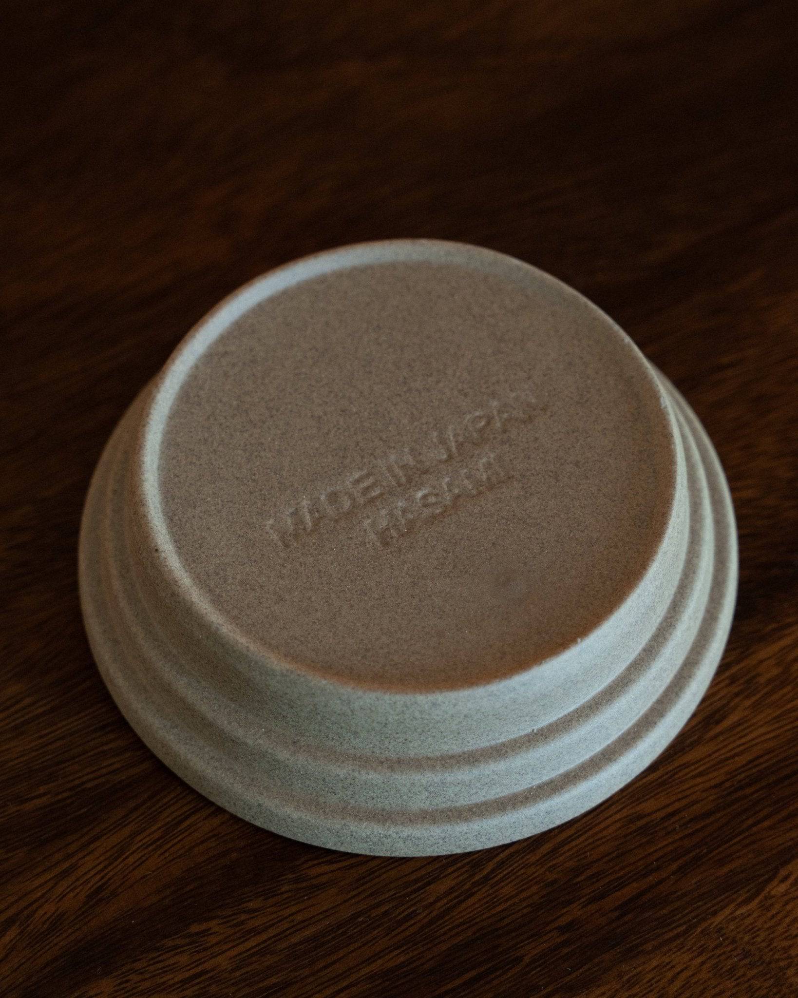 Kalita & HASAMI sandstone coffee dripper tray, showcasing Hasami-yaki craftsmanship. Circular design with raised center ring, textured matte finish. Made in Japan, suitable for various Kalita wave dripper models. Unique blend of traditional technique and modern style.