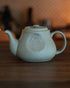 Kalita & HASAMI sandstone coffee pot, 700ml, in pale green. Traditional Hasami-yaki craftsmanship meets modern design. Teapot with embossed Kalita logo on wooden table, warm ambient lighting.