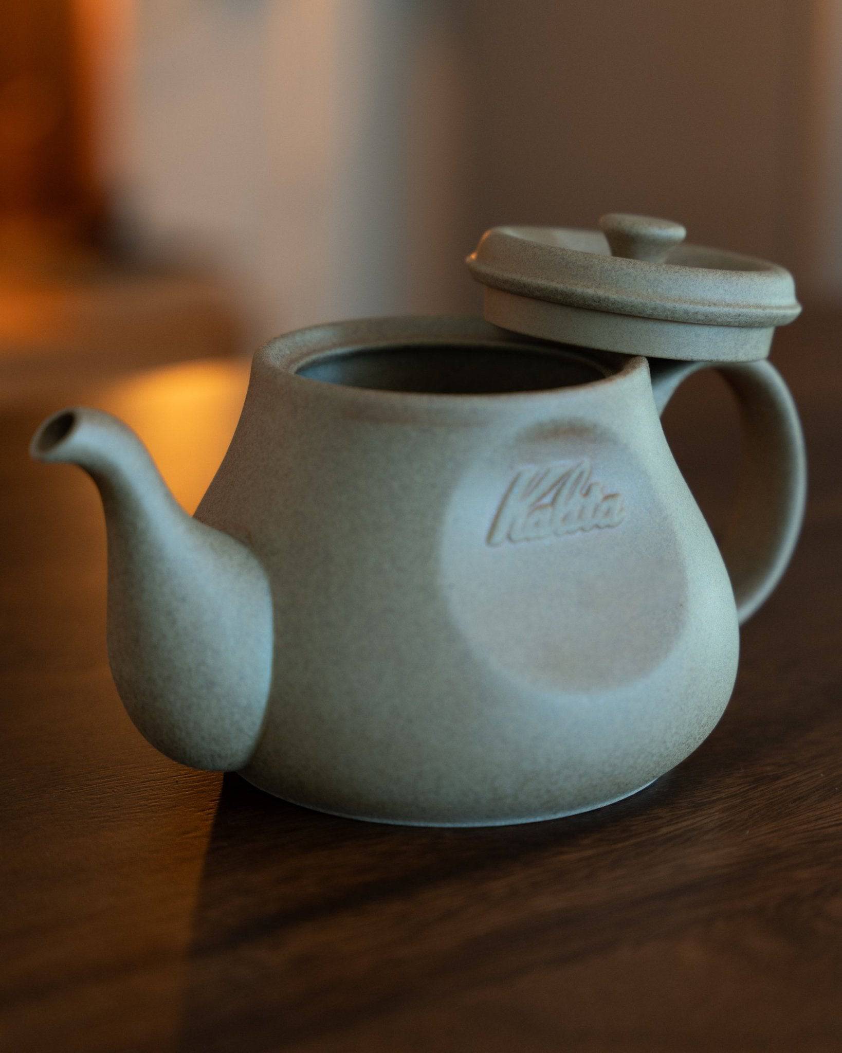Kalita & HASAMI sandstone coffee pot in soft gray, featuring a traditional teapot shape with a modern twist. The pot showcases a smooth texture, rounded body, curved spout, and lid with a unique handle design, embodying the fusion of Japanese craftsmanship and contemporary coffee culture.