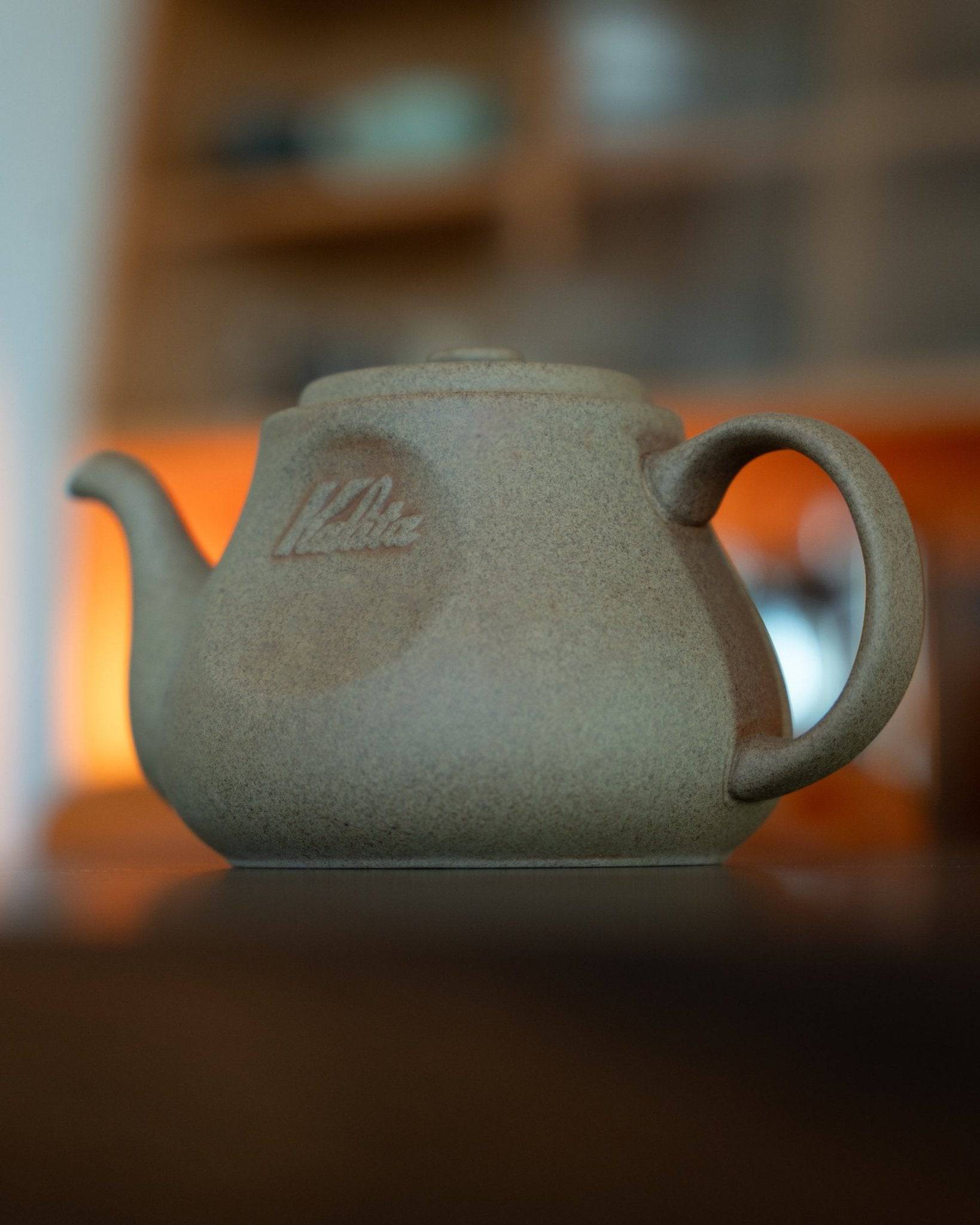 Kalita & HASAMI sandstone coffee pot in beige, featuring a traditional Japanese design with a modern twist. The 700ml pot showcases a textured surface, curved spout, and sturdy handle, set against a warm, blurred background.