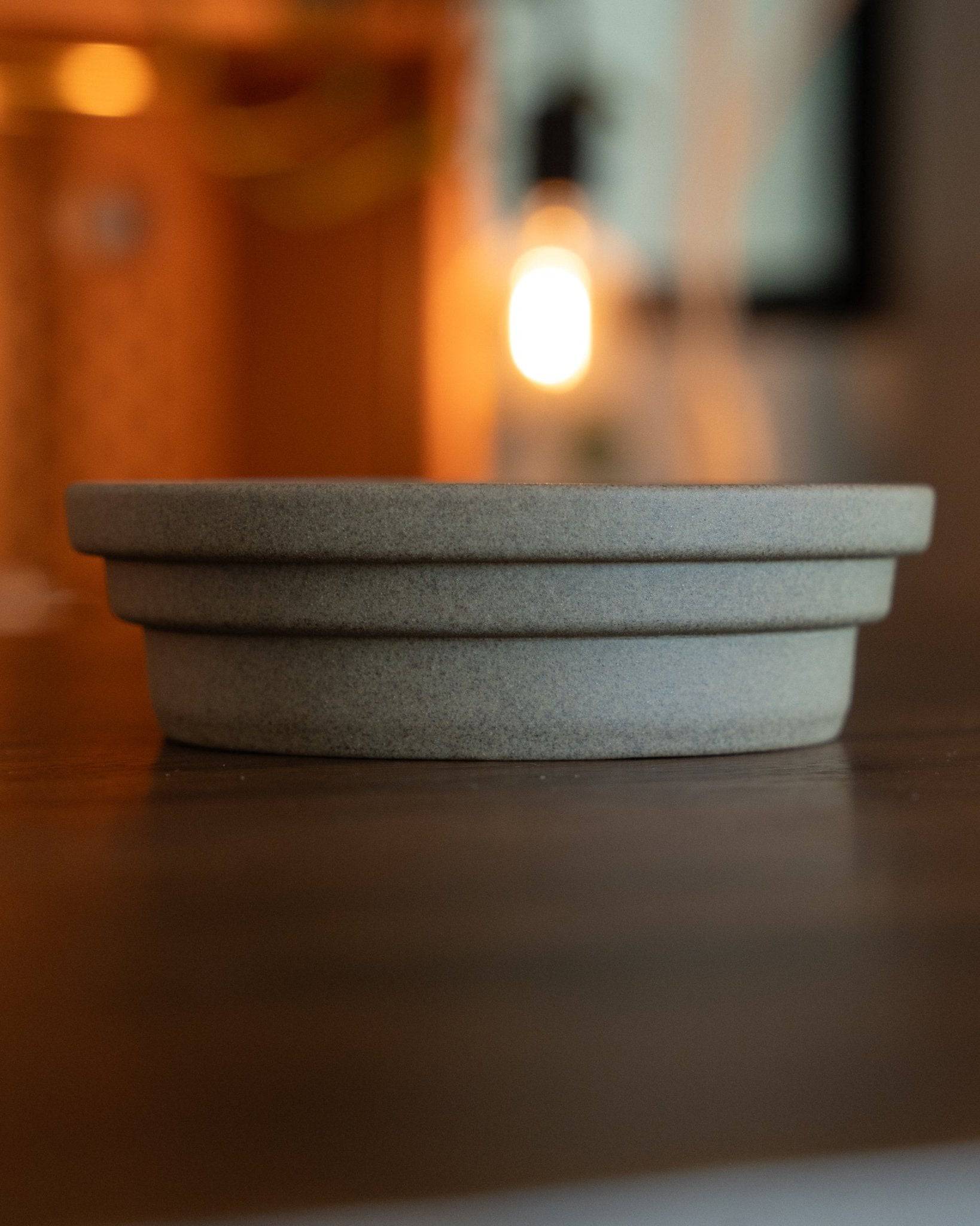 Kalita & HASAMI sandstone coffee dripper tray, showcasing Hasami-yaki craftsmanship. Circular design with raised center ring, textured matte finish. Japanese ceramic artistry for premium coffee brewing. Warm lighting highlights elegant simplicity.