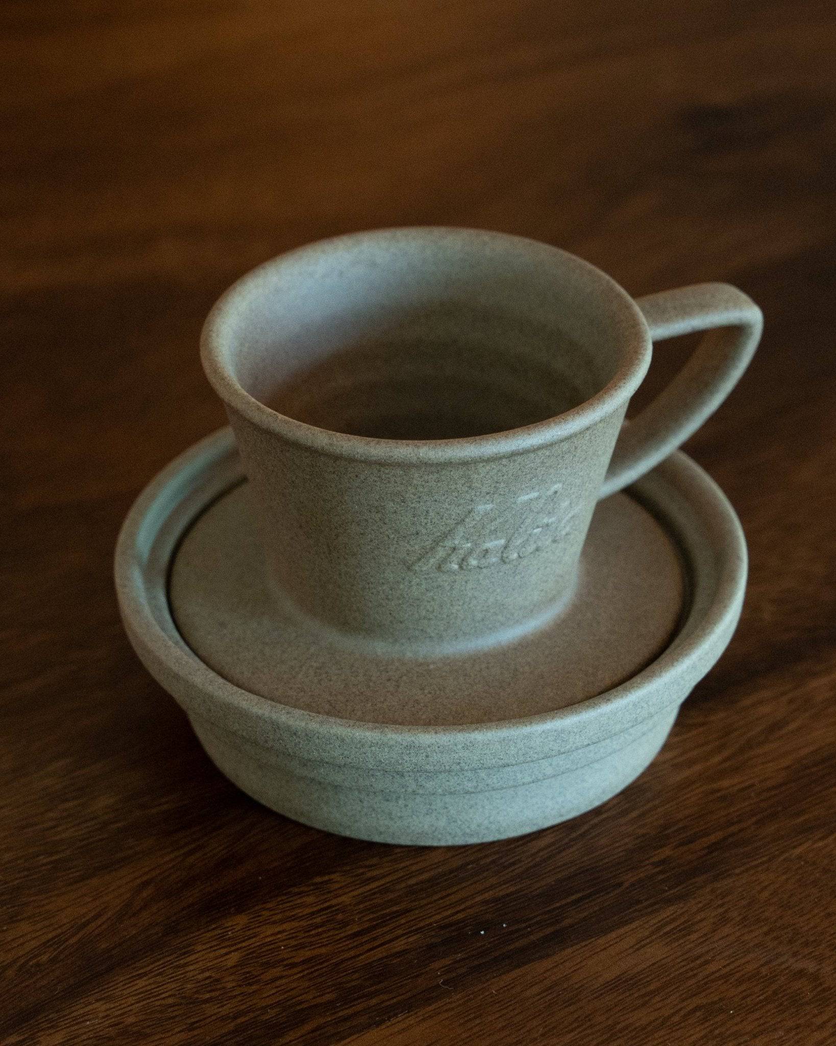 Kalita & HASAMI sandstone coffee dripper tray with cup, showcasing Japanese Hasami-yaki craftsmanship. Elegant gray ceramic set on wooden surface, featuring textured finish and minimalist design for premium coffee brewing experience.