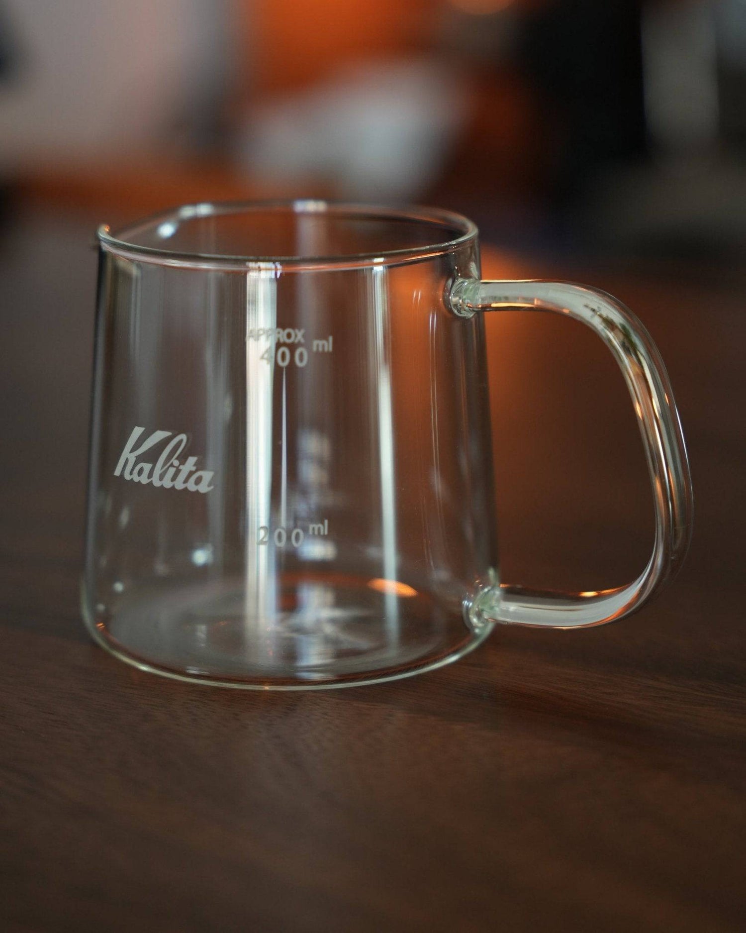 Kalita JUG400 heat-resistant glass coffee jug with 400ml capacity, featuring clear volume markings, ergonomic handle, and brand logo on a wooden surface