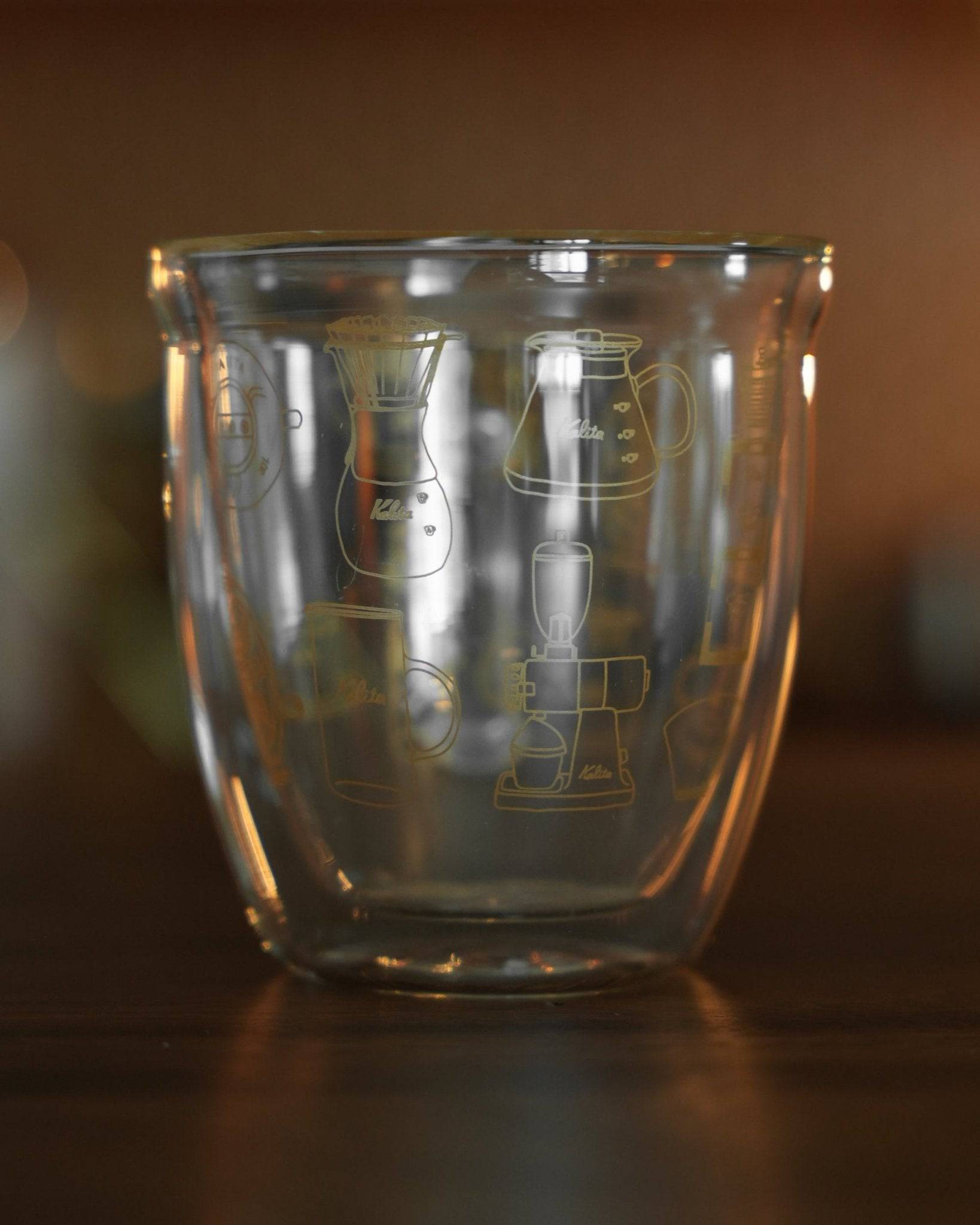 Kalita double-walled glass mug with coffee equipment illustrations, 340ml capacity, transparent design showcasing unique coffee-related etchings on surface, perfect for coffee enthusiasts and daily use