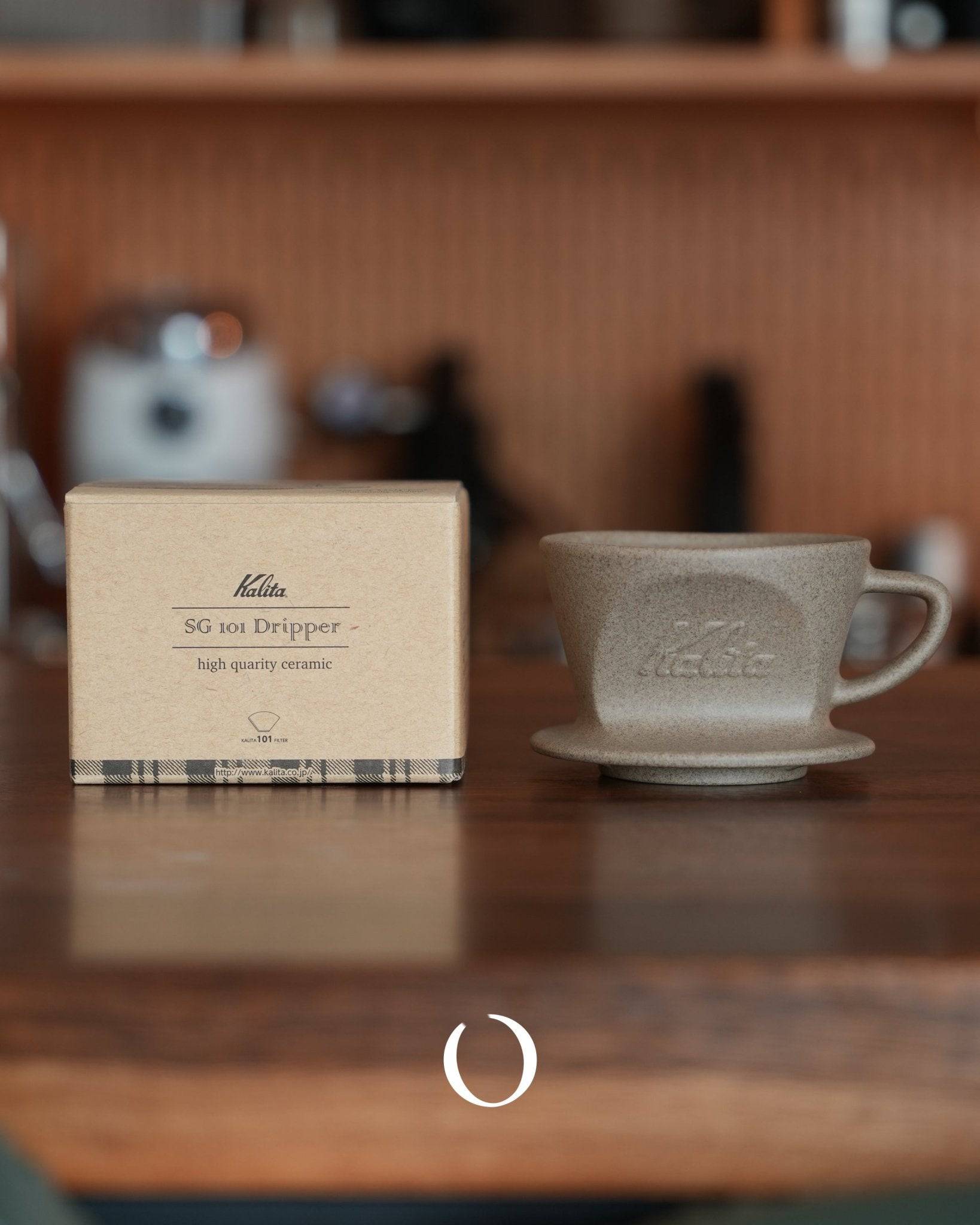 Kalita SG-101 ceramic coffee dripper with packaging box on wooden counter, showcasing high-quality sandstone clay Hasami-yaki craftsmanship for optimal coffee brewing and temperature retention