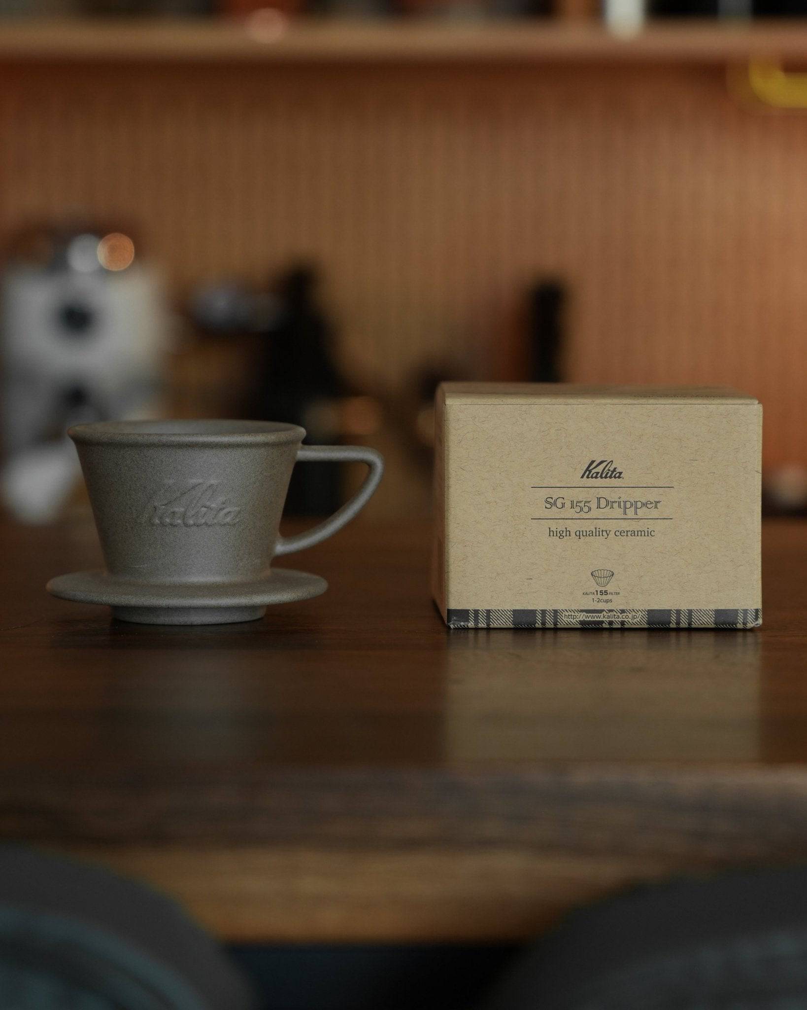 Kalita SG-155 Hasami-yaki sandstone dripper with its product box on wooden surface, showcasing traditional Japanese ceramic craftsmanship for premium coffee brewing