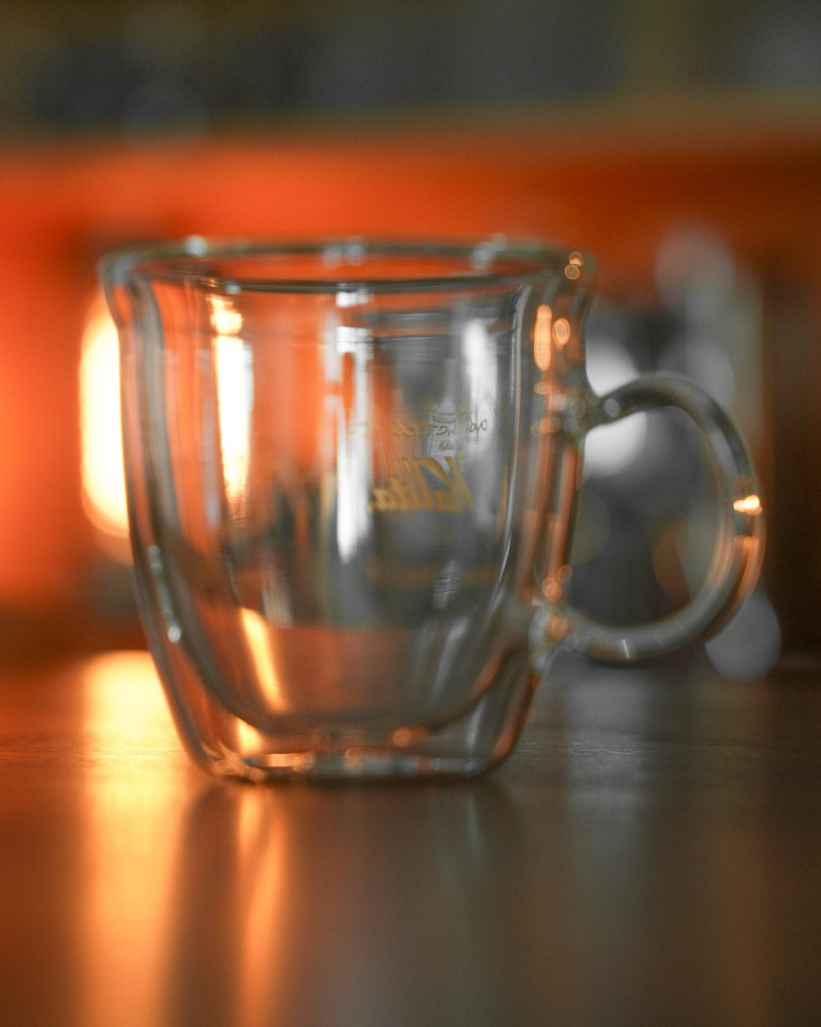 Kalita double-walled glass mug with engraved logo, transparent design showcasing insulation, warm ambient lighting, elegant curved handle, ideal for coffee enthusiasts