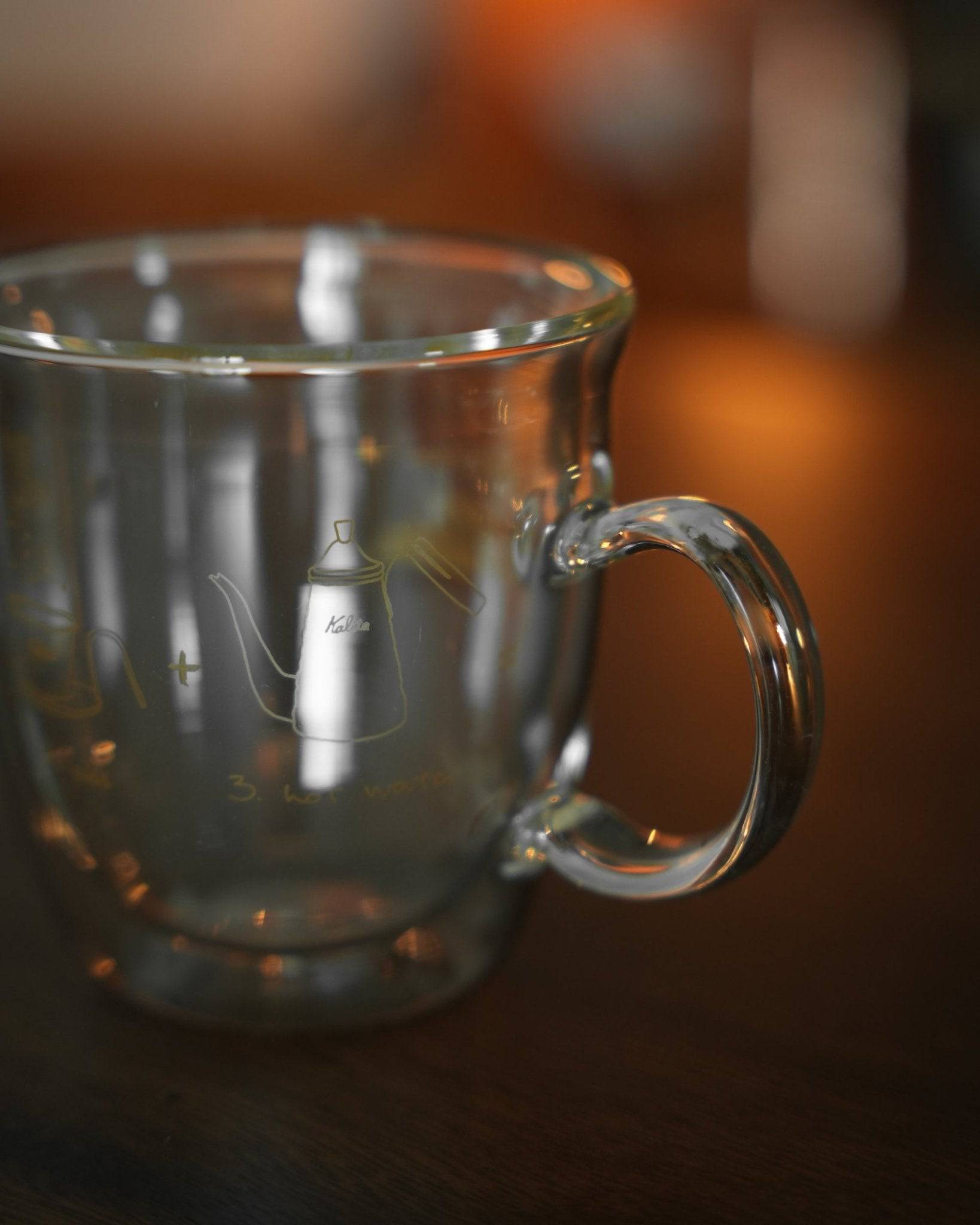 Kalita double-walled glass mug with coffee kettle design, showcasing transparent construction, vacuum insulation, and elegant handle. Close-up view highlighting durability and heat retention for optimal coffee enjoyment.