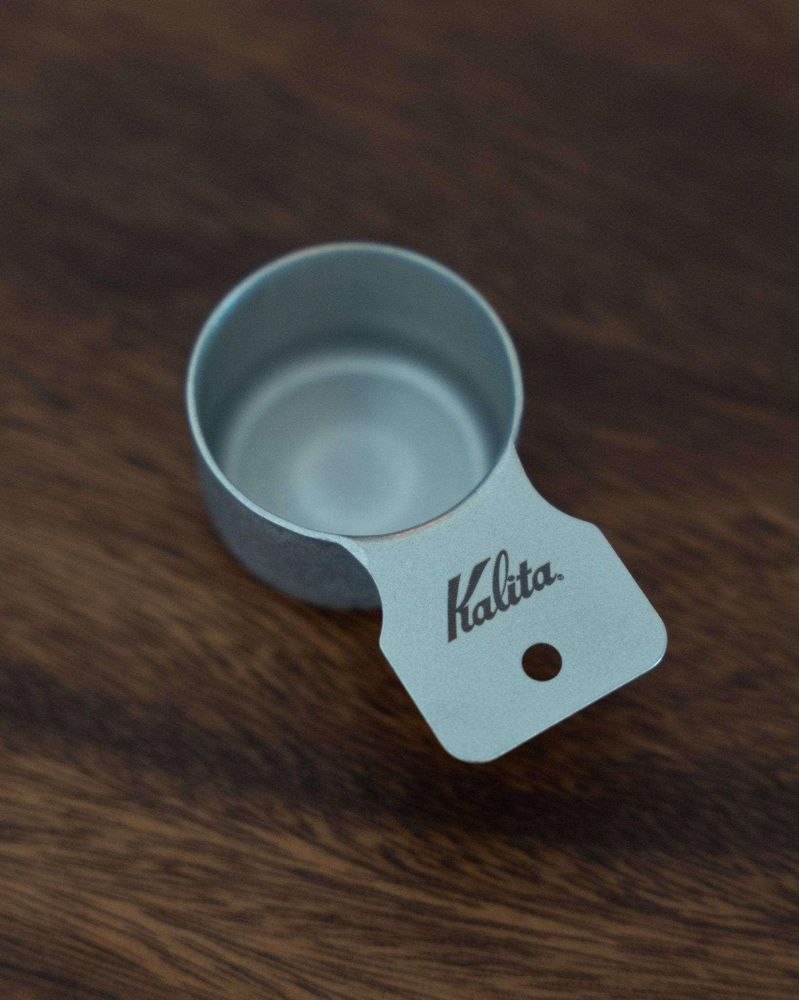 Kalita & Tsubame stainless steel coffee measuring scoop, 10g capacity, S Size, with matte finish and Kalita branding, placed on a dark wooden surface