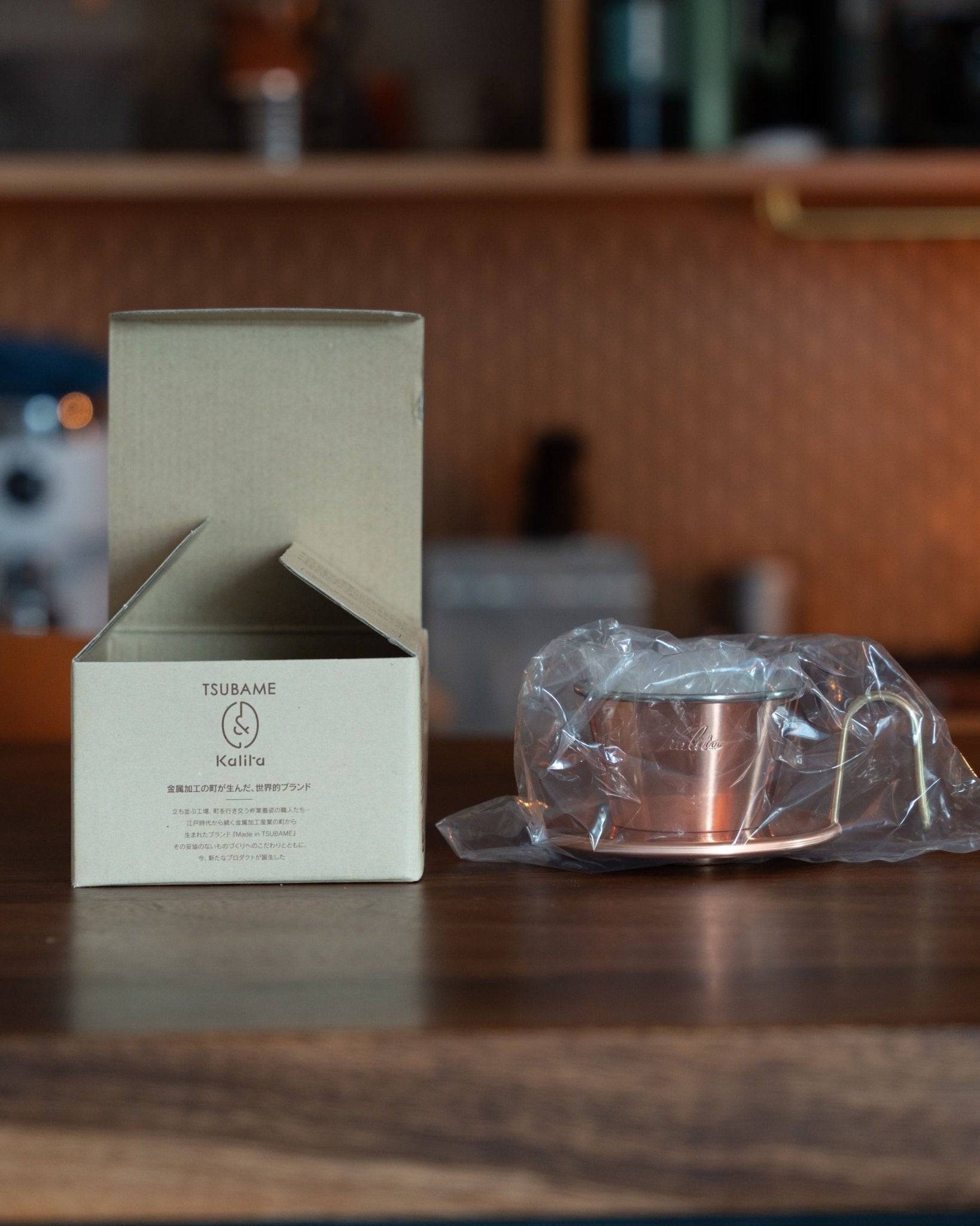 Kalita & TSUBAME WDC-155 copper coffee dripper with packaging box and wrapped product on wooden table, showcasing premium handcrafted Japanese coffee equipment for pour-over brewing