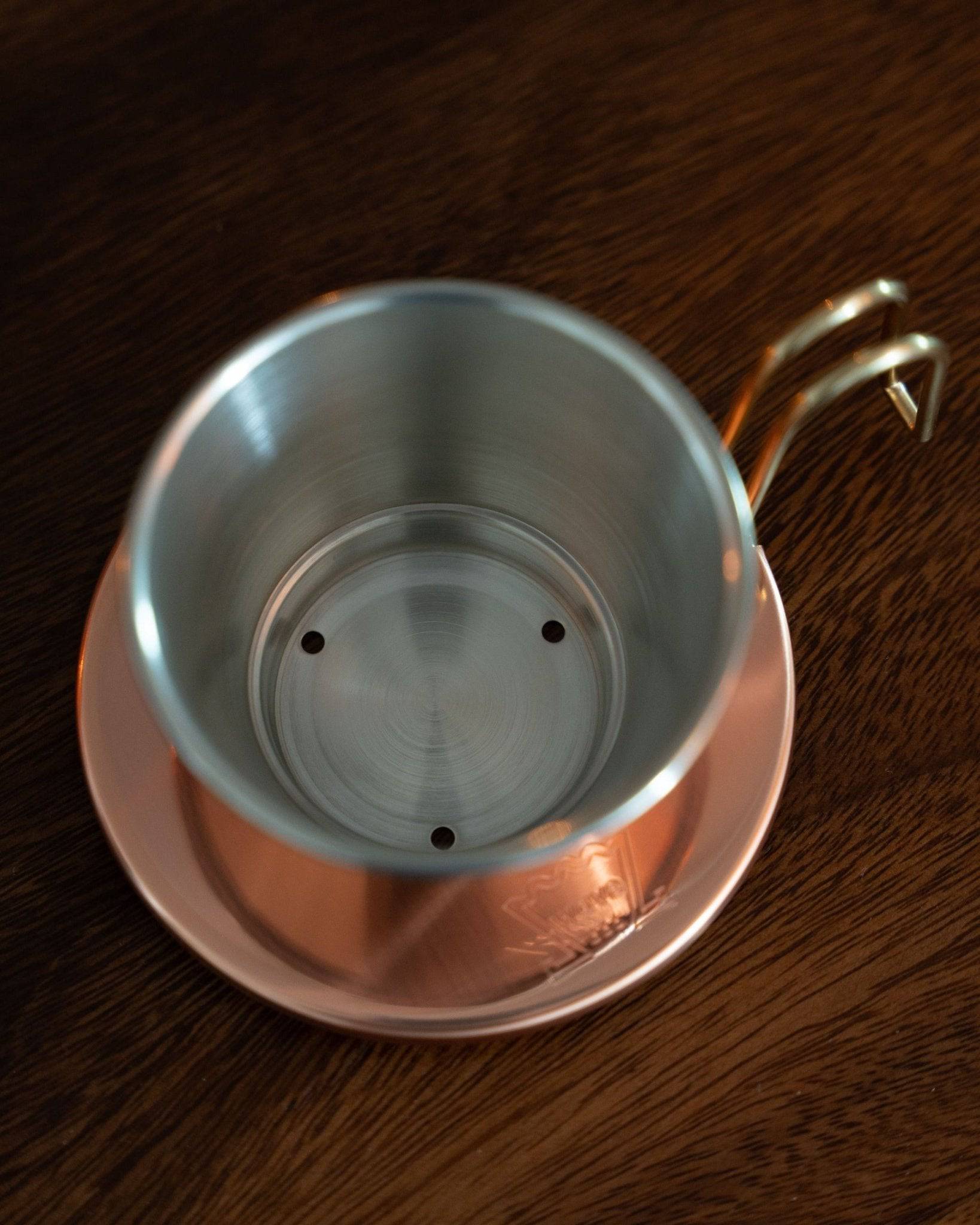 Kalita & TSUBAME WDC-155 copper pour-over coffee dripper with three-hole design, showcasing interior stainless steel and exterior copper construction, placed on a wooden surface, highlighting its craftsmanship and heat conduction properties for optimal coffee brewing