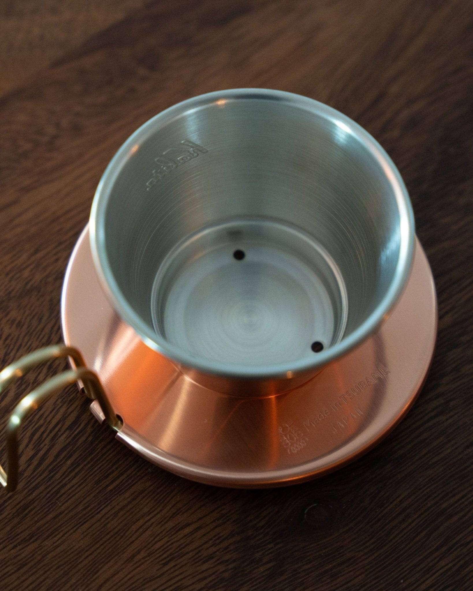 Kalita & TSUBAME WDC-155 copper coffee dripper with three-hole design, showcasing its silver interior and copper exterior on a wooden surface, highlighting its craftsmanship and heat conduction properties for optimal coffee brewing