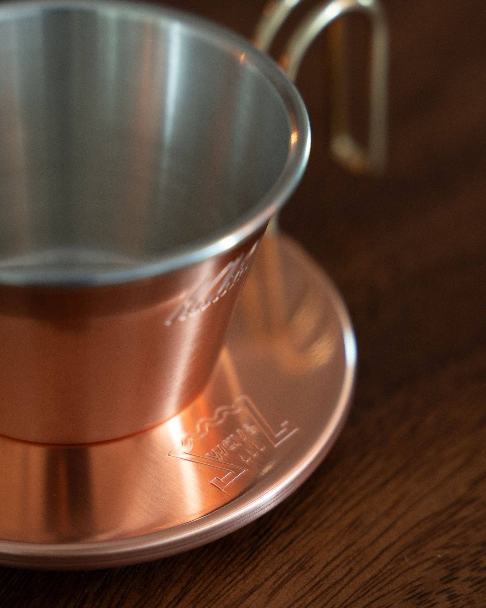 Copper Kalita & TSUBAME WDC-155 pour-over coffee dripper on wooden surface, showcasing its elegant design with shiny interior and matte exterior finish, highlighting the brand&