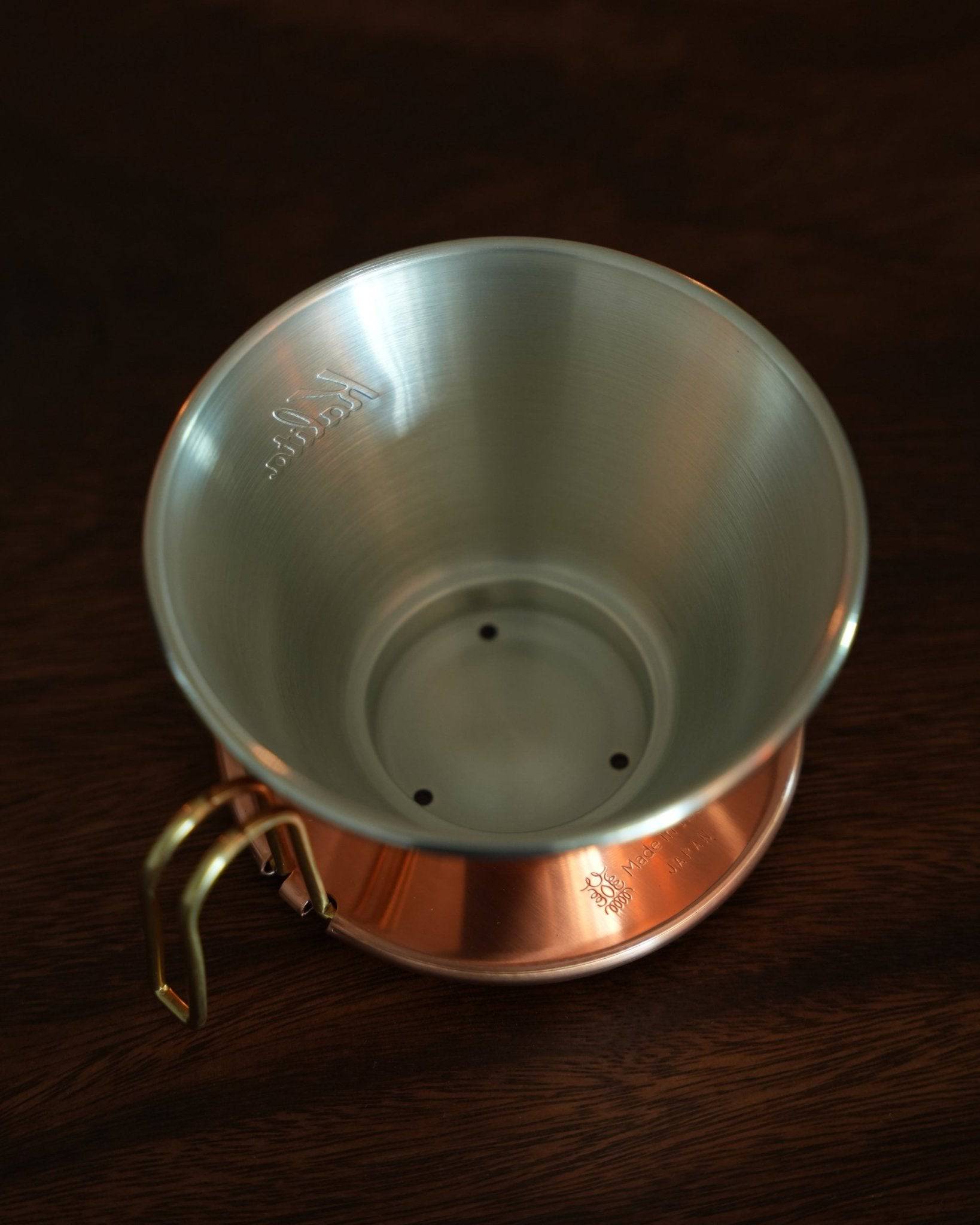 Kalita & TSUBAME WDC-185 copper coffee dripper with three-hole design, handcrafted in Japan. Interior view showing stainless steel lining and bottom holes. Copper exterior with brass handle visible. Elegant and functional design for premium coffee brewing.