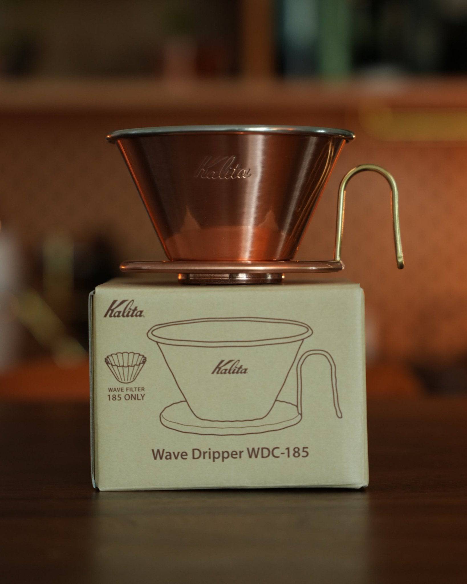 Kalita & TSUBAME WDC-185 copper wave dripper on its packaging box, showcasing the gleaming copper cone with three-hole design and gold-colored wire handle. The box illustrates the dripper&