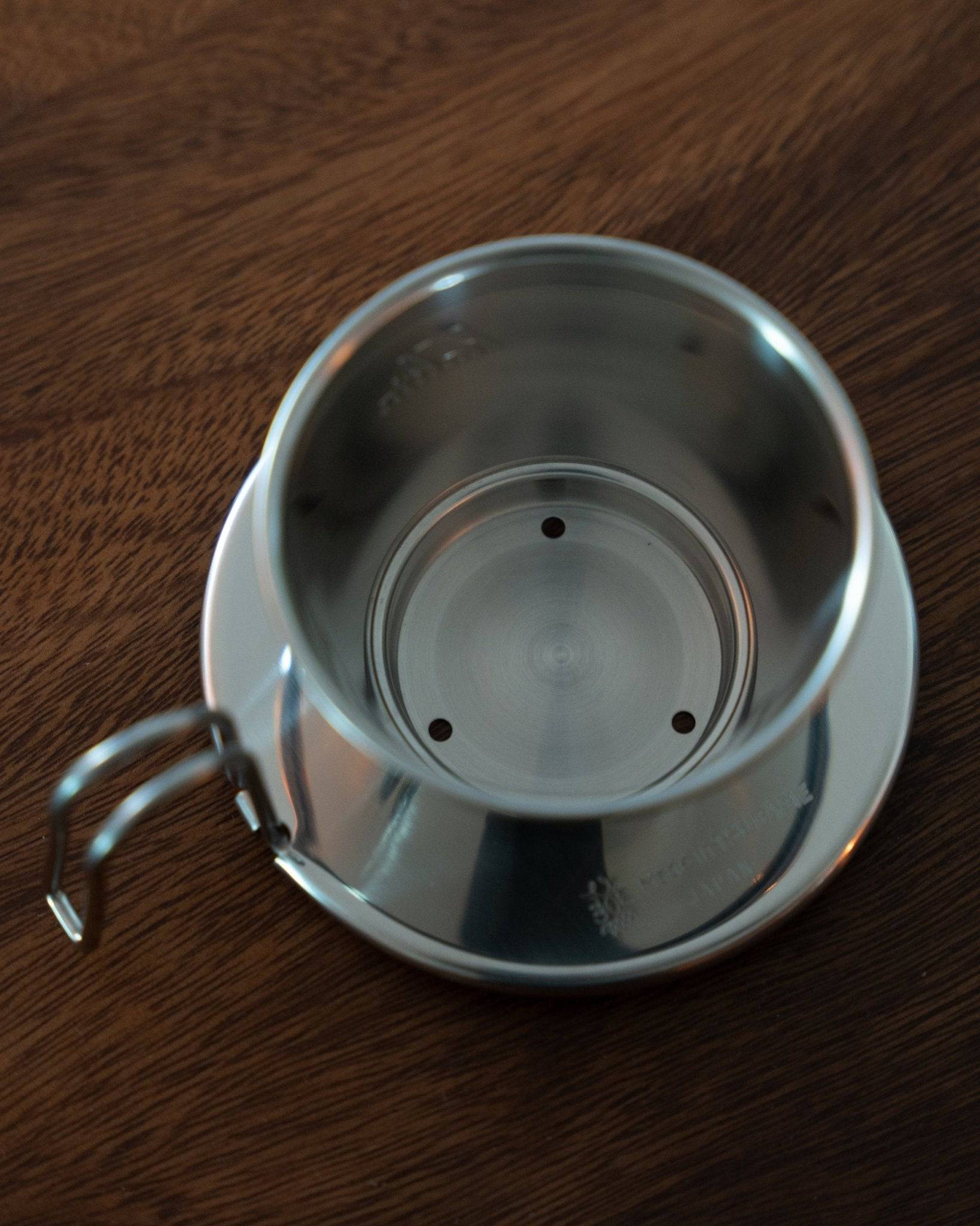 Kalita & TSUBAME WDS-155 stainless steel coffee dripper with three-hole design on wooden surface, showcasing its elegant shape and high-quality craftsmanship for optimal coffee brewing