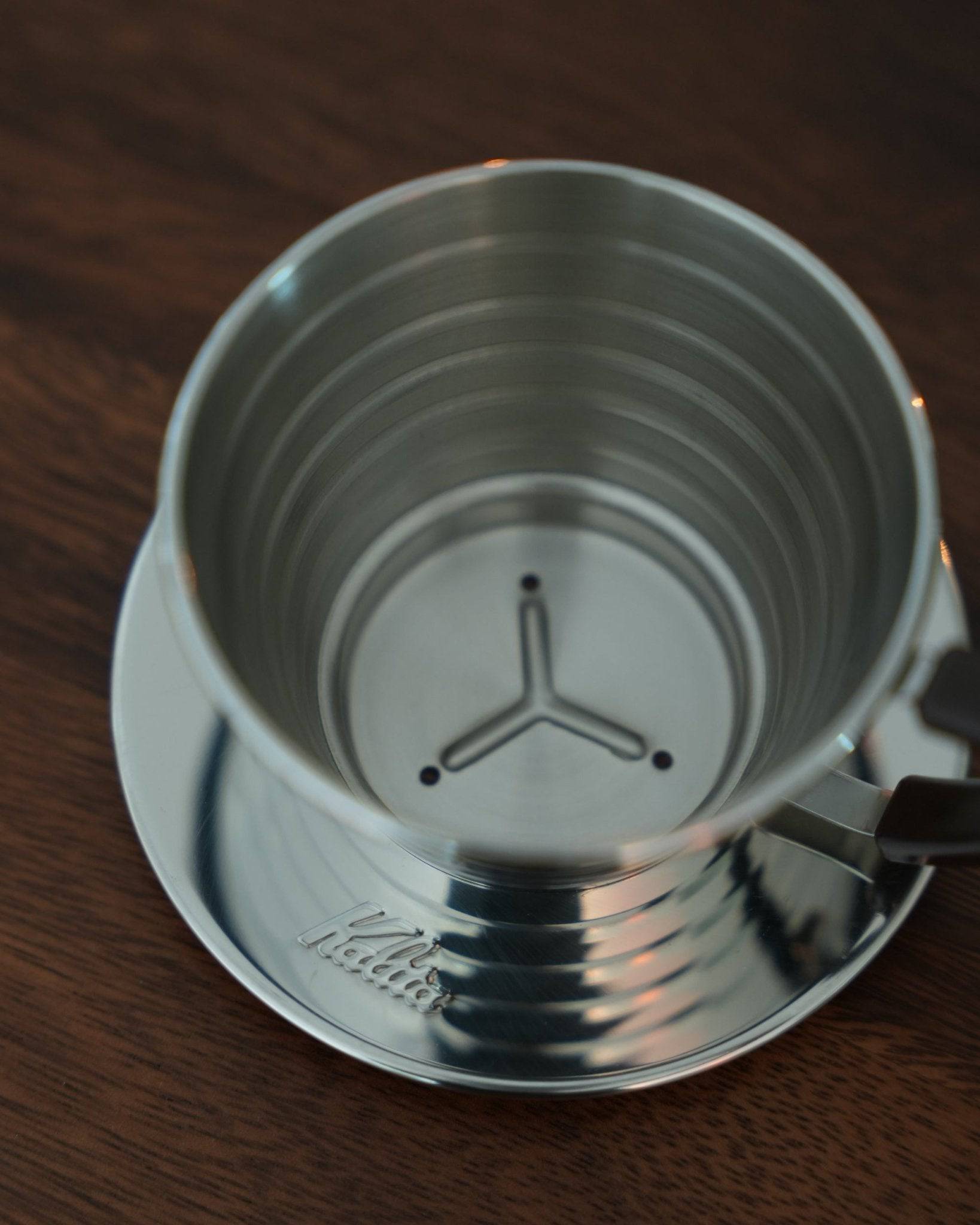 Stainless steel Kalita Wave 155 coffee dripper with distinctive wave pattern and three-hole design, showcasing its unique brewing features and premium craftsmanship for pour-over coffee enthusiasts