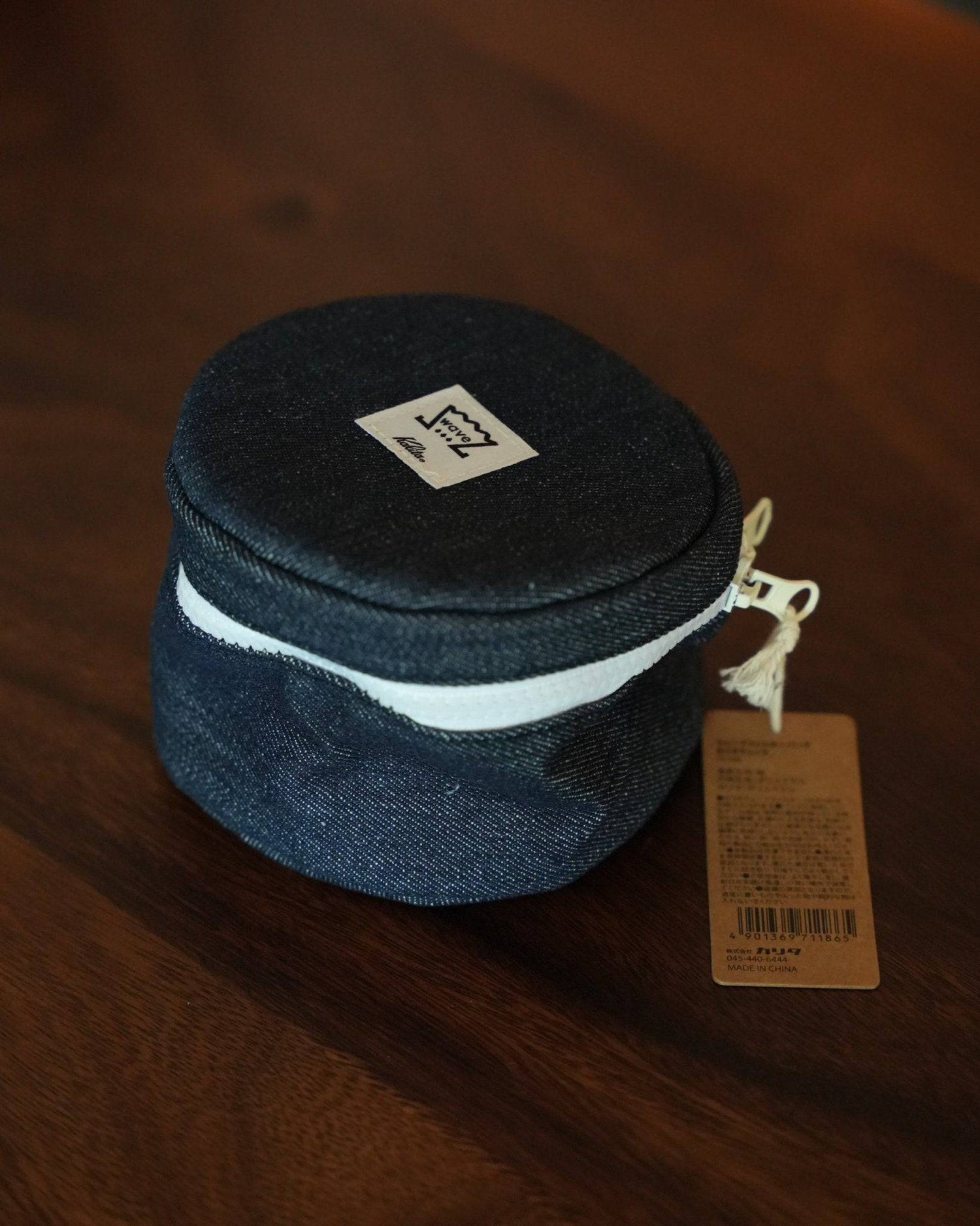 Kalita Wave coffee filter storage bag in dark denim with white zipper and brand logo, displayed on wooden surface with product tag attached
