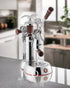 La Pavoni Esperto Abile espresso machine with chrome body, wooden handles, pressure gauges, and eagle-shaped steam knob on kitchen counter