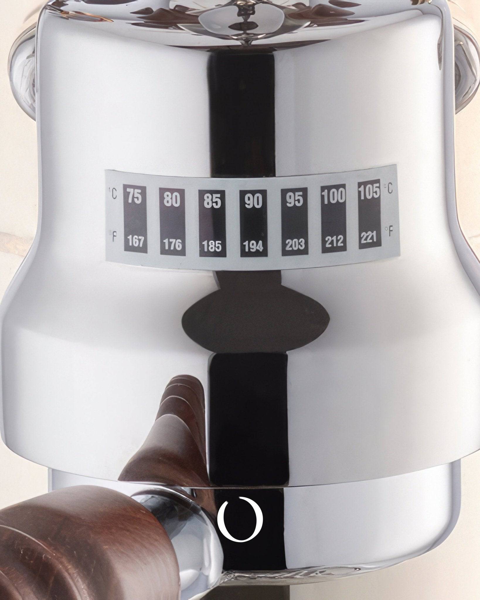 Close-up of La Pavoni Esperto Competente espresso machine boiler with temperature gauge displaying Celsius and Fahrenheit scales, shiny chrome finish, and wooden handle visible in foreground