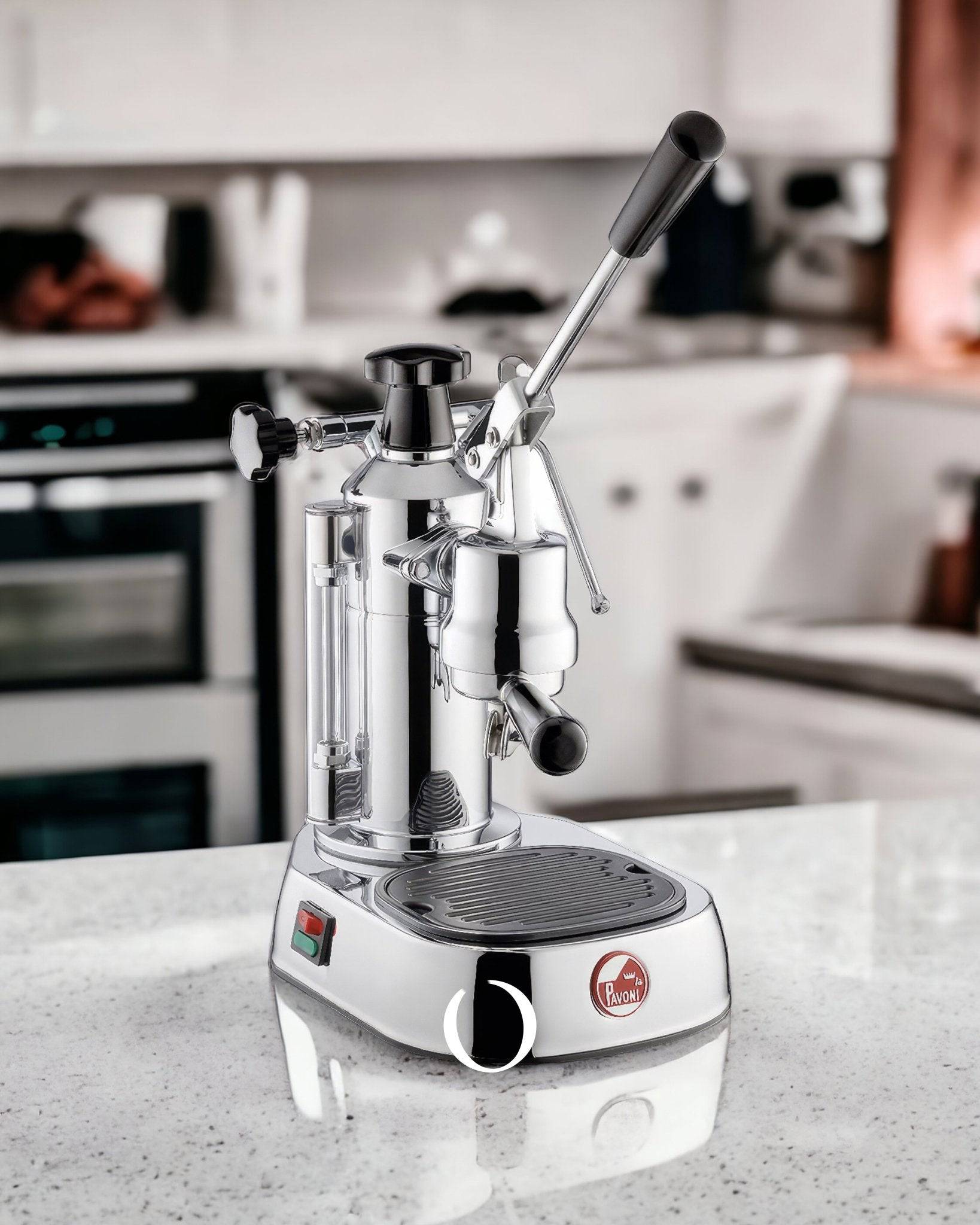 La Pavoni Europiccola Lusso lever espresso machine on kitchen counter, featuring chrome body, black handle, and drip tray. Professional-grade manual coffee maker for home baristas.