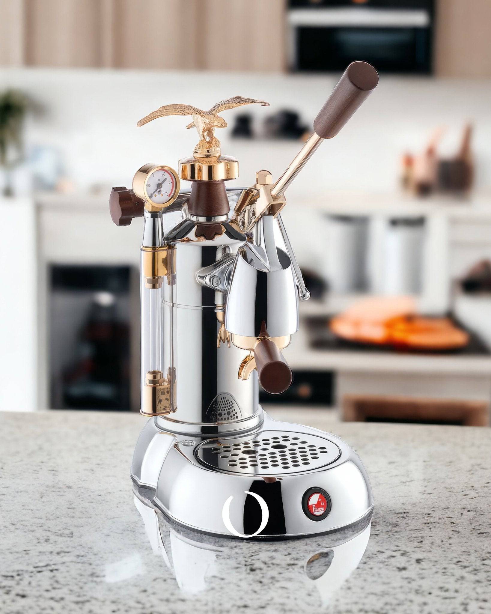 La Pavoni EXPO Lever Espresso Machine on kitchen counter, featuring gold eagle emblem, wooden handle, pressure gauge, and chrome finish. Luxurious design with vintage-inspired details and professional-grade components for crafting authentic Italian espresso.