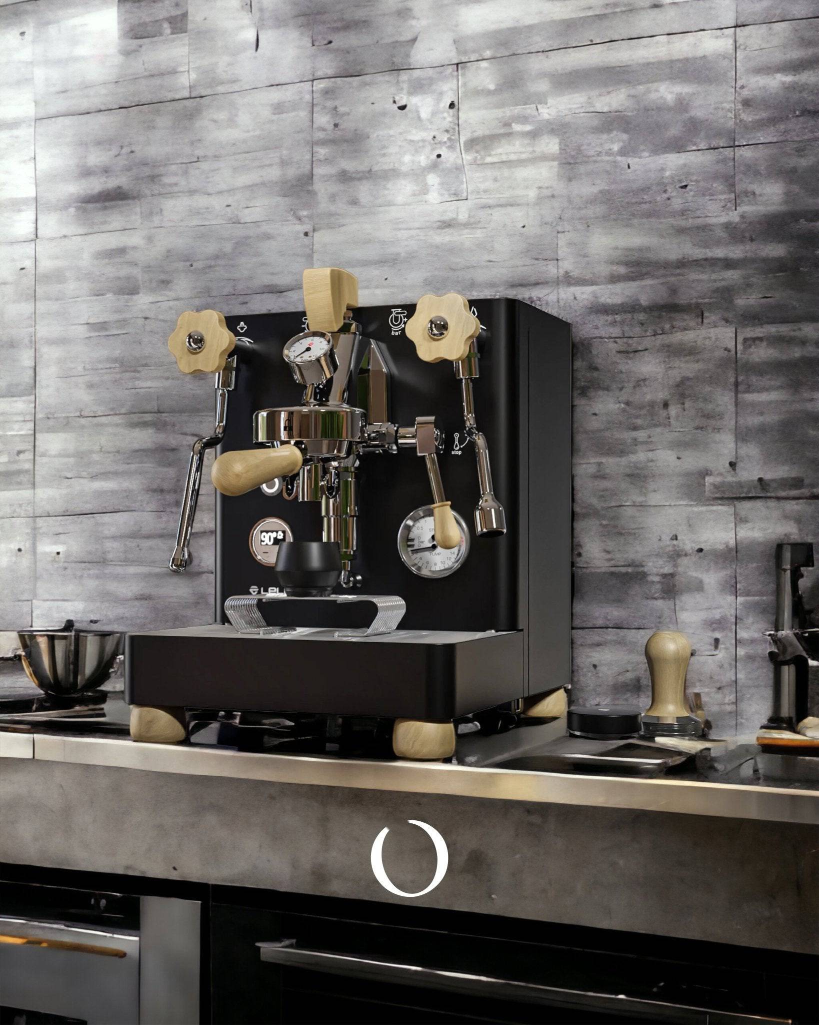 Lelit Bianca V3 espresso machine in black with wooden accents, showcased on a modern kitchen counter against a concrete wall backdrop. Professional-grade coffee maker with dual boilers and flow control features.