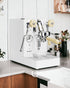 Lelit MaraX V2 PL62X white special edition espresso machine on kitchen counter, featuring stainless steel body with gold accents, pressure gauge, and wooden handle details