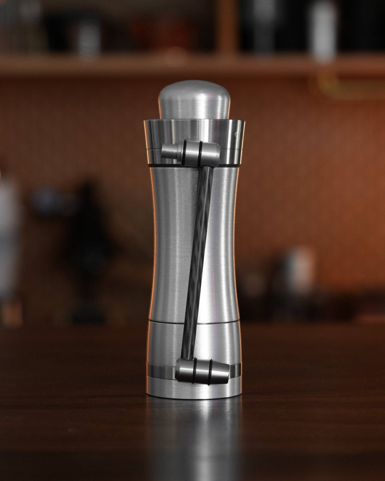 Mazzer Omega Fast manual coffee grinder with sleek stainless steel design, featuring a carbon fiber handle and compact body for portable, high-speed grinding, suitable for various brewing methods from espresso to French press