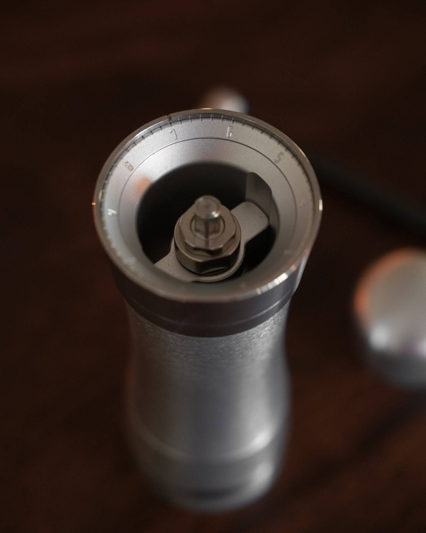 Mazzer Omega Soft manual coffee grinder with adjustable settings, featuring a sleek silver body and precision burr grinder visible through the top opening, showcasing its professional-grade design for optimal coffee grinding at home or on-the-go