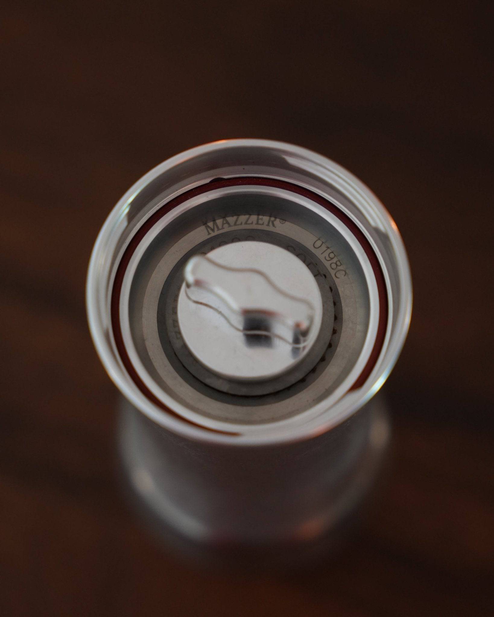 Top view of Mazzer Omega Soft manual coffee grinder, showing the precision-engineered grinding mechanism with Mazzer branding visible on the circular metal surface, highlighting its professional-grade design for coffee enthusiasts.