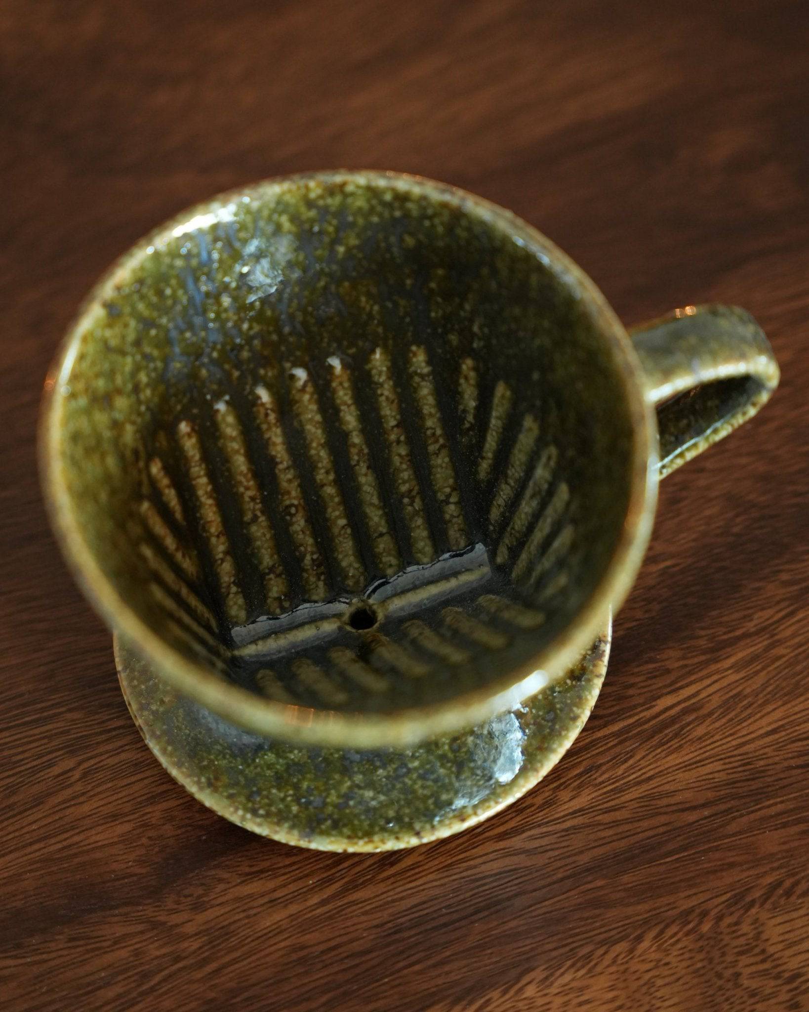 Melitta yellow-green ceramic pour-over coffee dripper with unique fan-shaped single hole design, showcasing Minoyaki craftsmanship on wooden surface