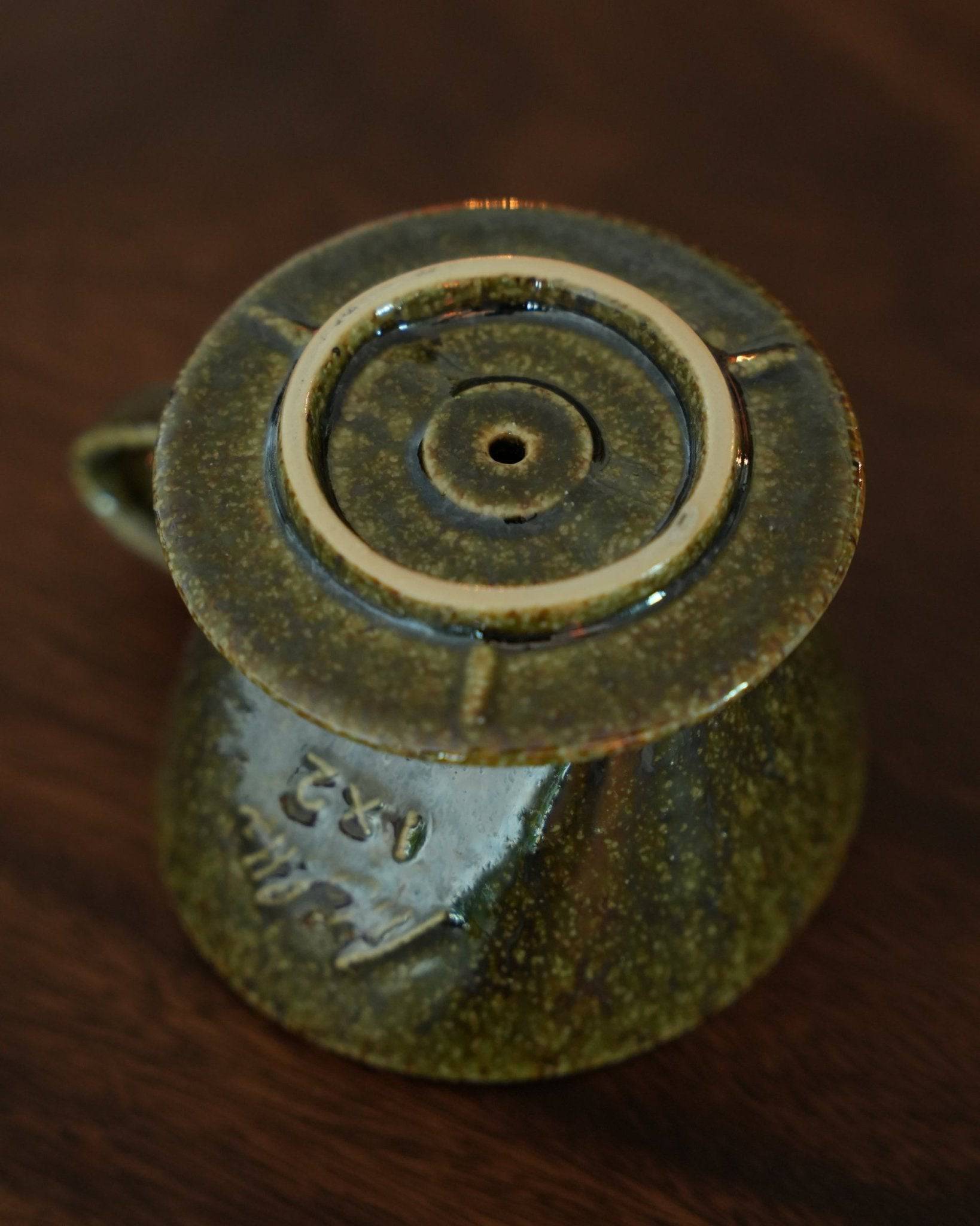 Melitta yellow-green ceramic pour-over coffee dripper with unique fan-shaped single hole design, showcasing traditional Minoyaki craftsmanship and modern aesthetics, on a wooden surface