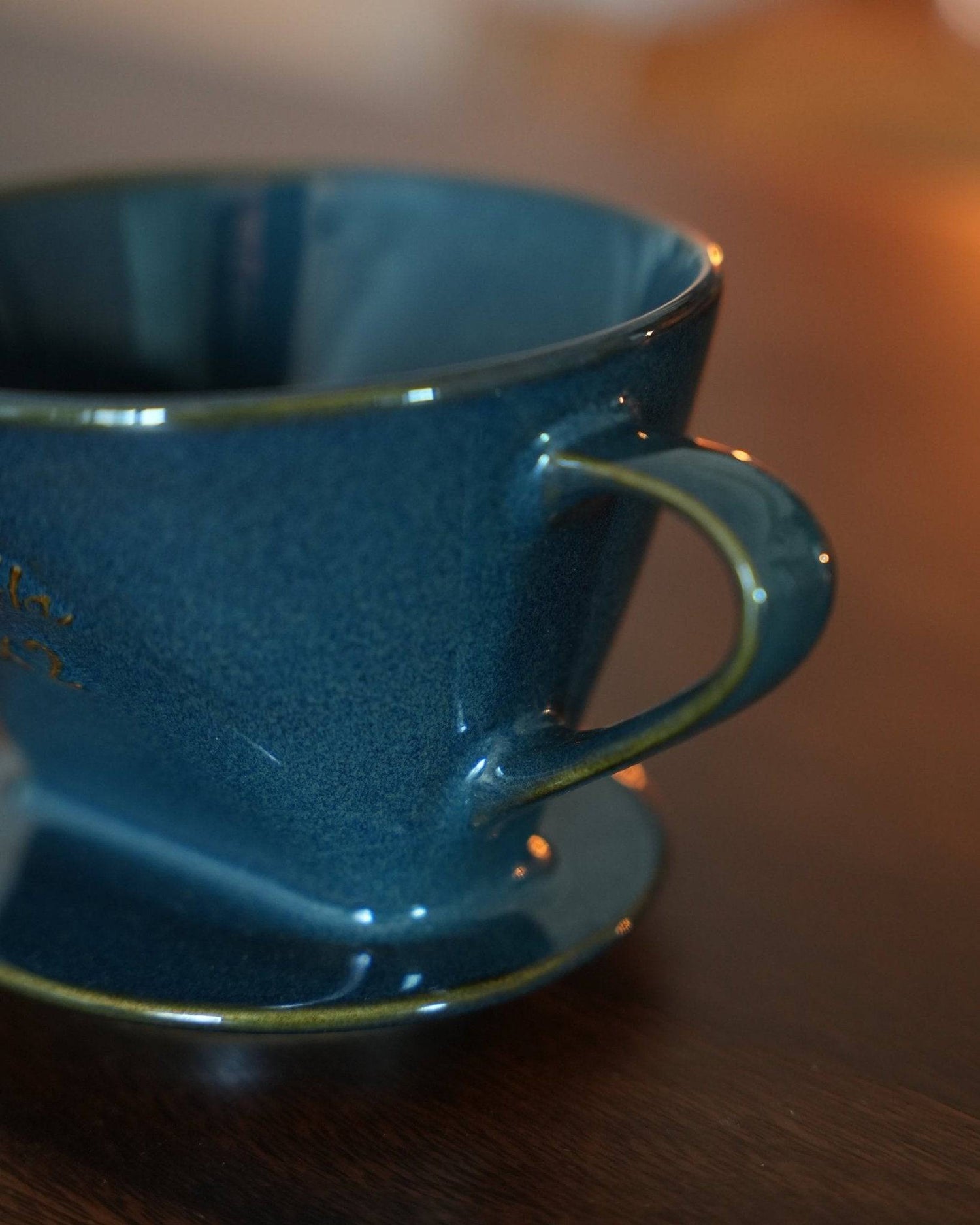 Melitta turquoise blue coffee dripper close-up, showcasing its elegant ceramic design, unique fan-shaped hole, and glossy finish. Perfect for brewing 2-4 cups of artisanal coffee.