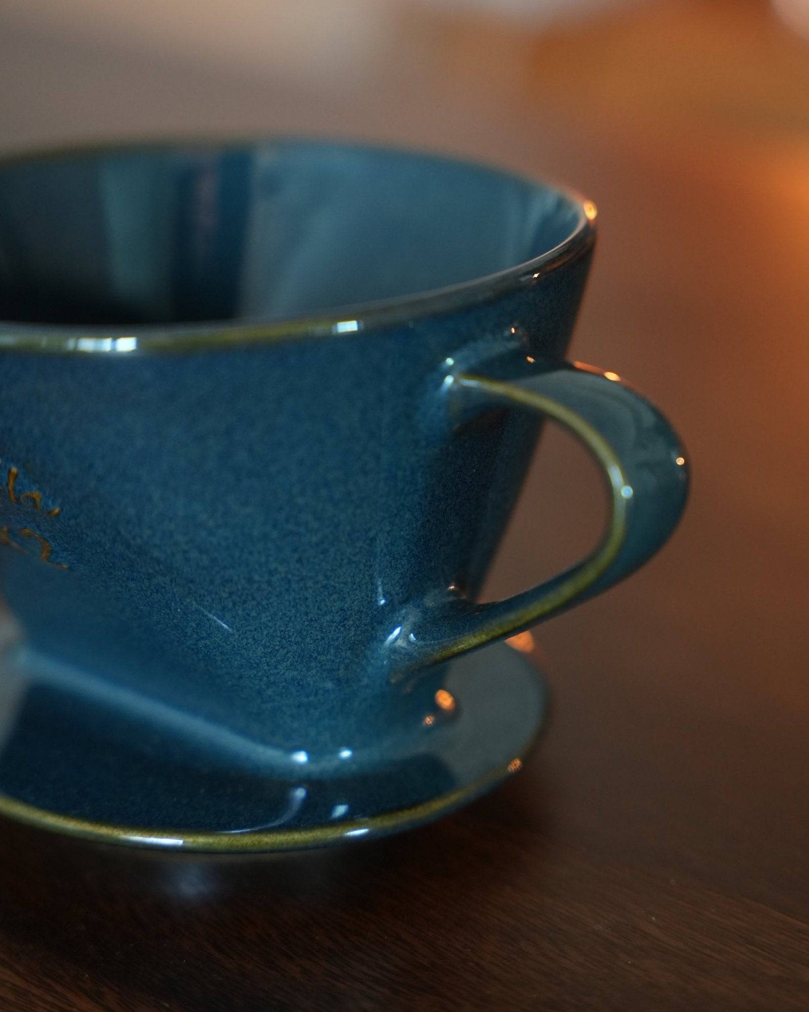 Melitta turquoise blue coffee dripper close-up, showcasing its elegant ceramic design, unique fan-shaped hole, and glossy finish. Perfect for brewing 2-4 cups of artisanal coffee.