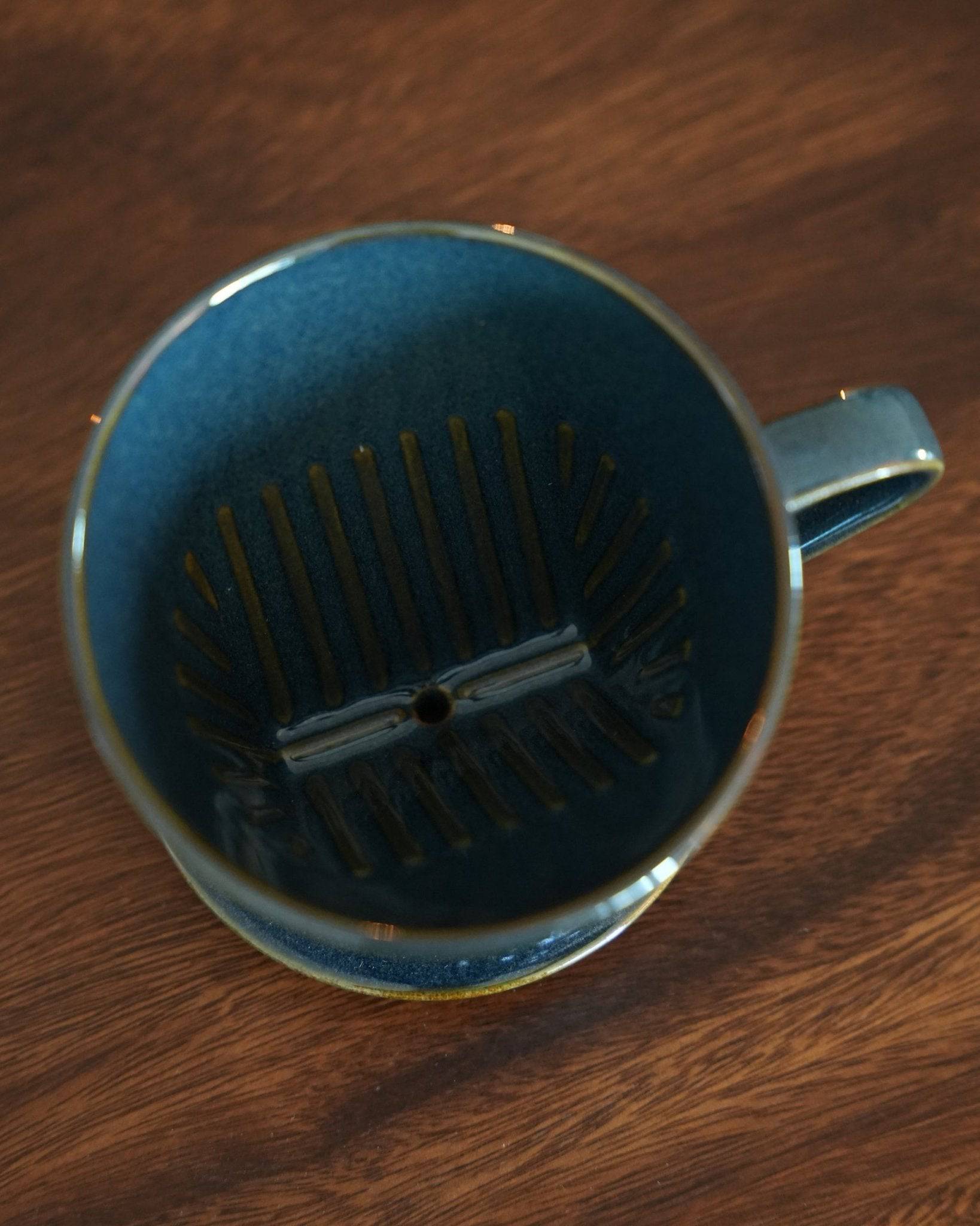 Melitta turquoise blue coffee dripper with fan-shaped single hole design and ribbed interior, showcasing traditional Mino-yaki craftsmanship on a wooden surface
