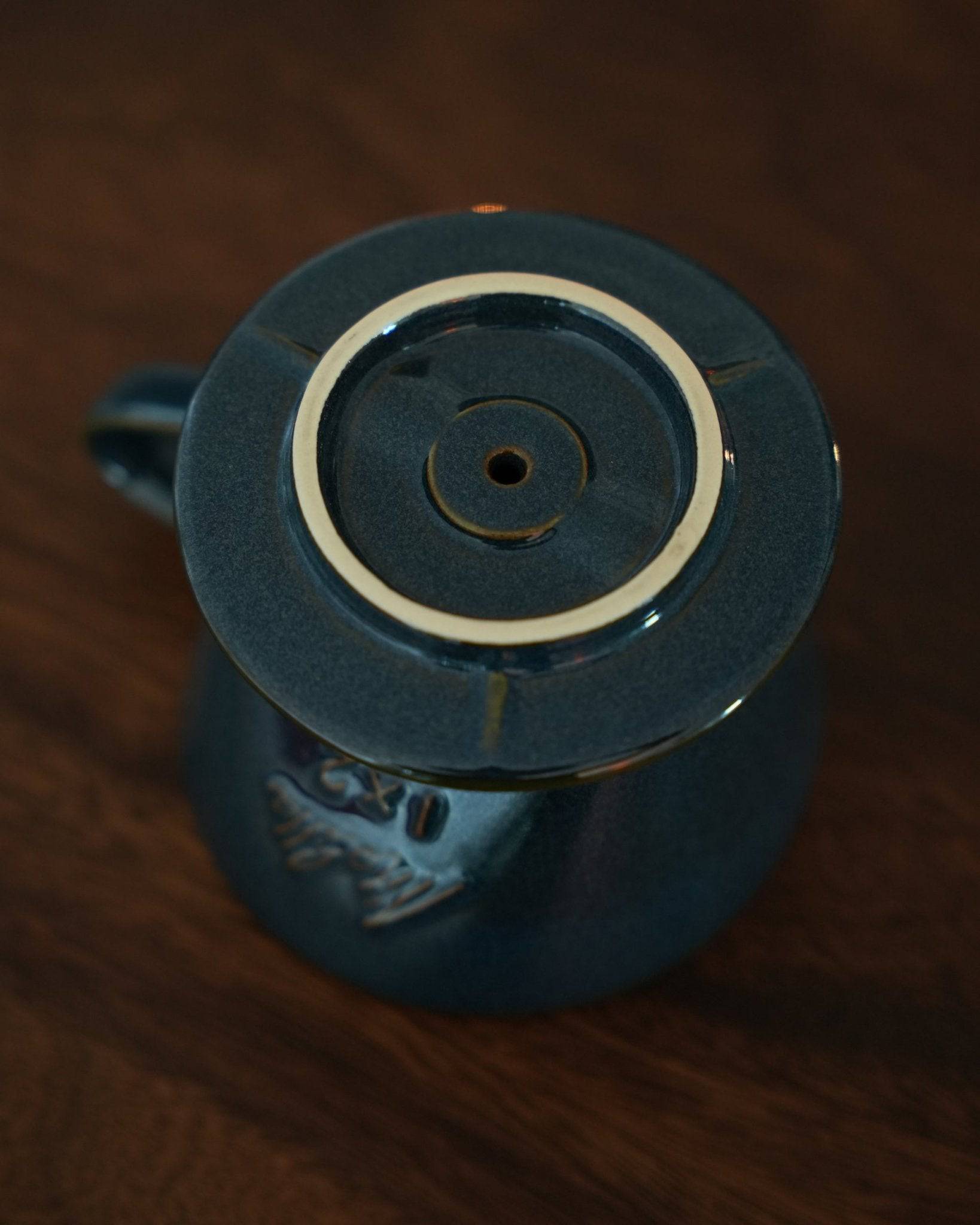 Melitta turquoise blue pour-over coffee dripper, top view showcasing unique single fan-shaped hole design, ceramic craftsmanship, and elegant color on wooden surface