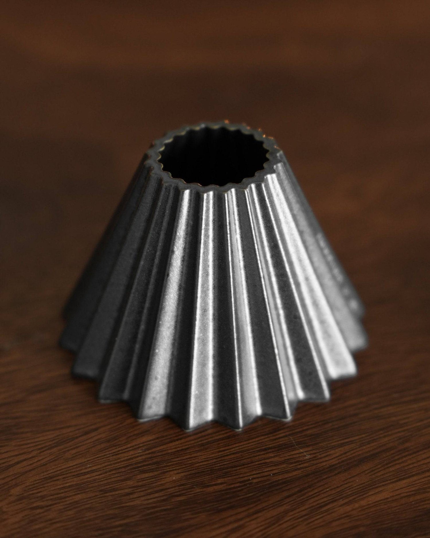 Ninety Plus Coffee Kone 10.1 mini dripper, conical shape with ridged exterior, metallic black finish, designed for 10g coffee brewing, sitting on wooden surface