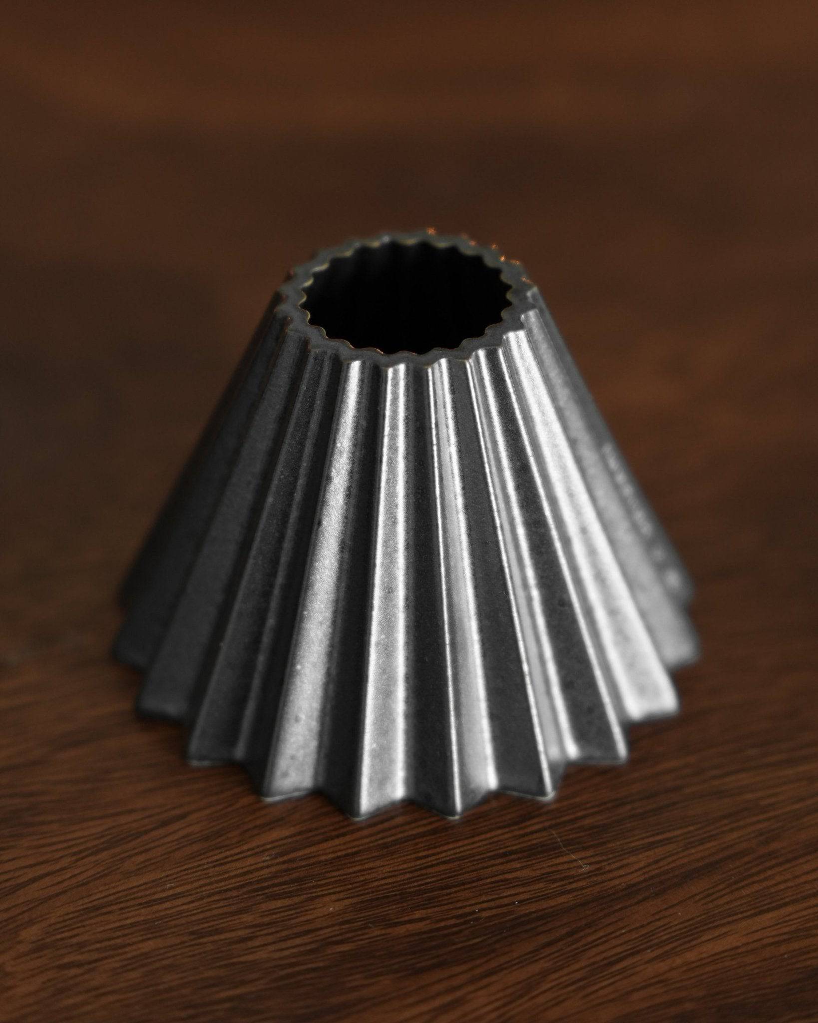 Ninety Plus Coffee Kone 10.1 mini dripper, conical shape with ridged exterior, metallic black finish, designed for 10g coffee brewing, sitting on wooden surface
