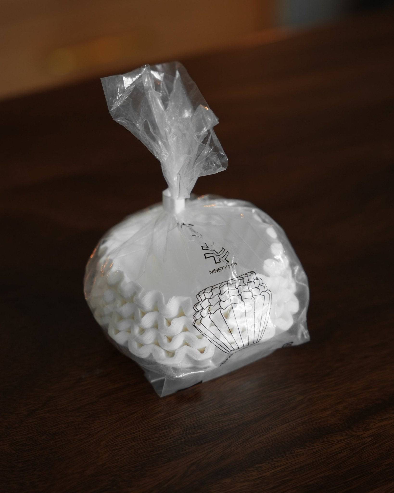 Ninety Plus Coffee Kone Filter 10.1 flat-bottom paper filters in a transparent plastic package, showcasing the product&