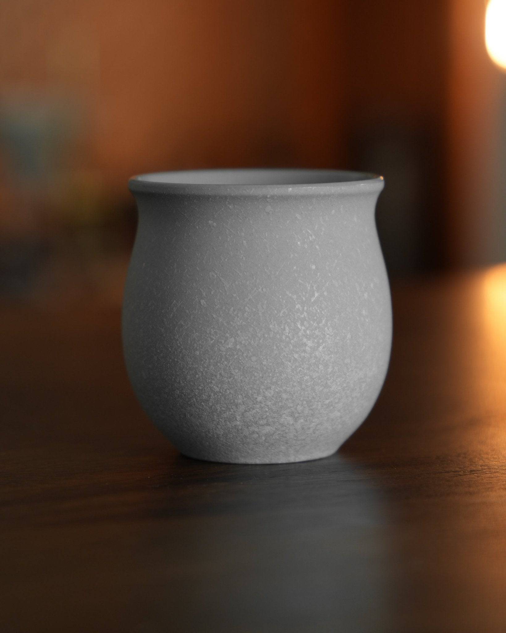 Ninety Plus Coffee Savour Cup in matte white, inspired by basalt rock, on a wooden surface with warm lighting, designed for direct extraction and pure enjoyment of specialty coffee