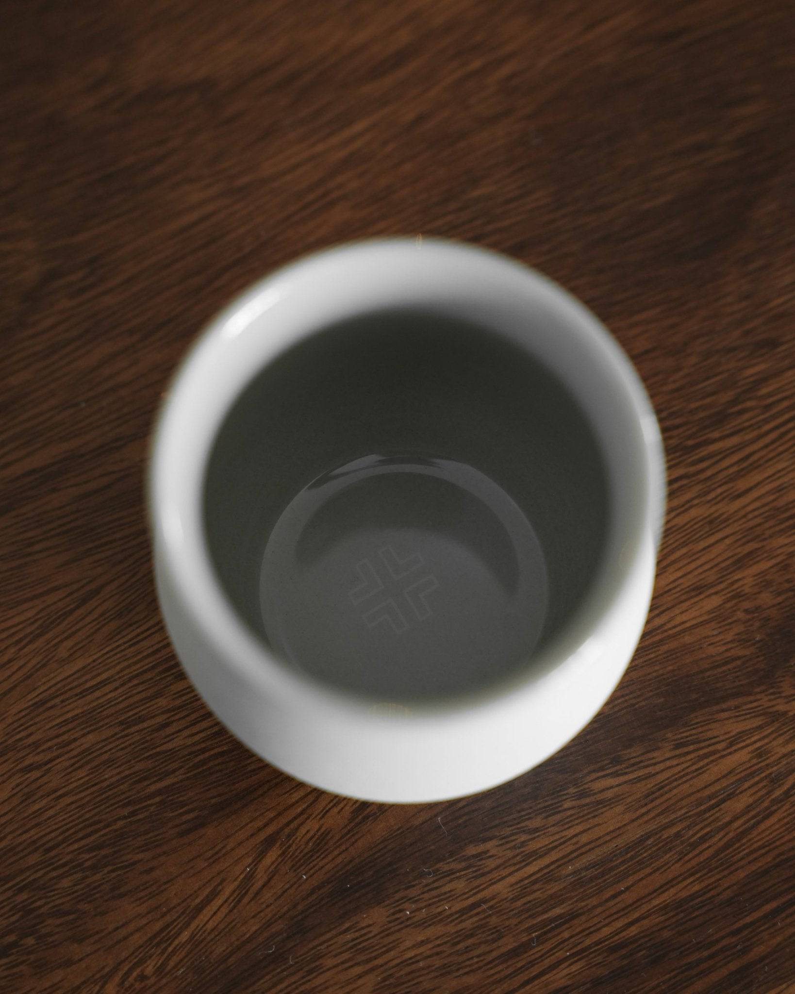 Ninety Plus Coffee Savour Cup 10.1 in Basalt white, viewed from above on a wooden surface. The cup&