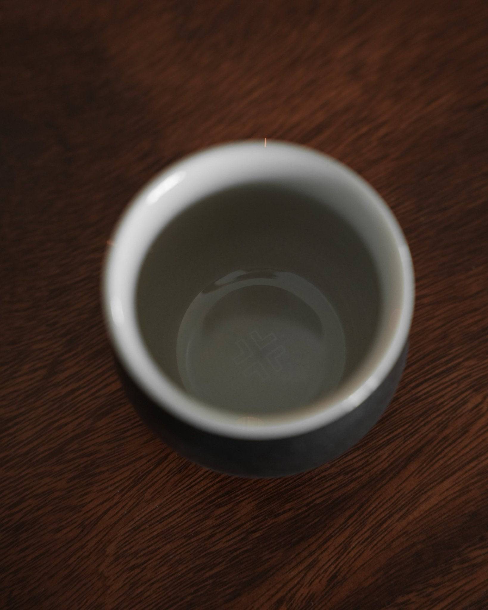 Ninety Plus Coffee Savour Cup 10.1 in Obsidian black, showcasing its elegant design inspired by volcanic soil. The cup sits on a dark wooden surface, highlighting its sleek form and premium quality for specialty coffee enthusiasts.