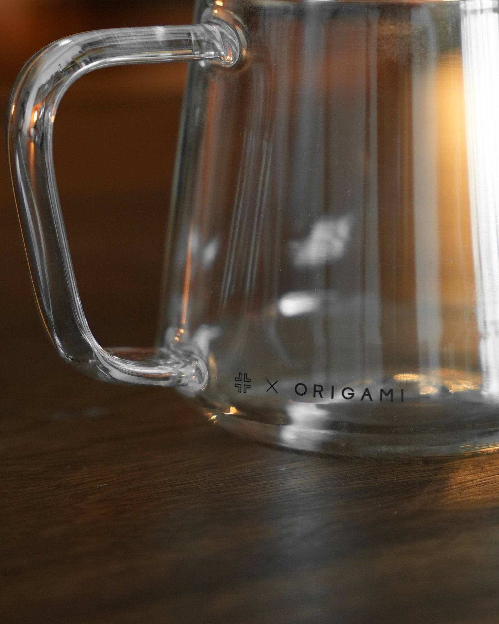 Clear glass Ninety Plus Coffee serving pitcher with Origami branding, showcasing elegant design and precise coffee distribution capabilities, perfect for sharing premium coffee experiences