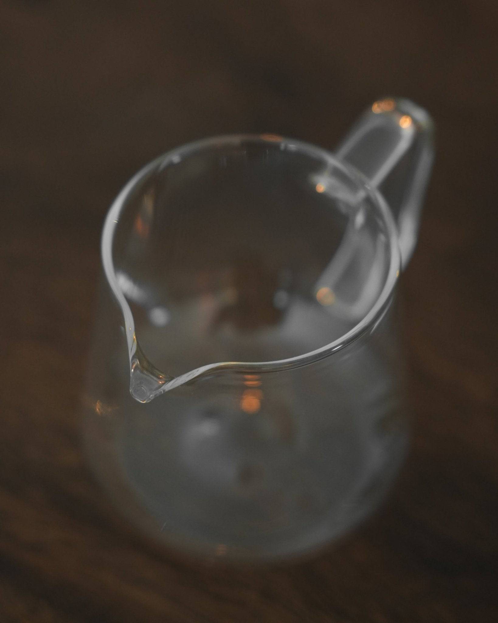 Transparent glass coffee serving pitcher by Ninety Plus, designed for precise pour-over brewing and elegant sharing of premium coffee, compatible with Origami drippers, on a dark wooden surface