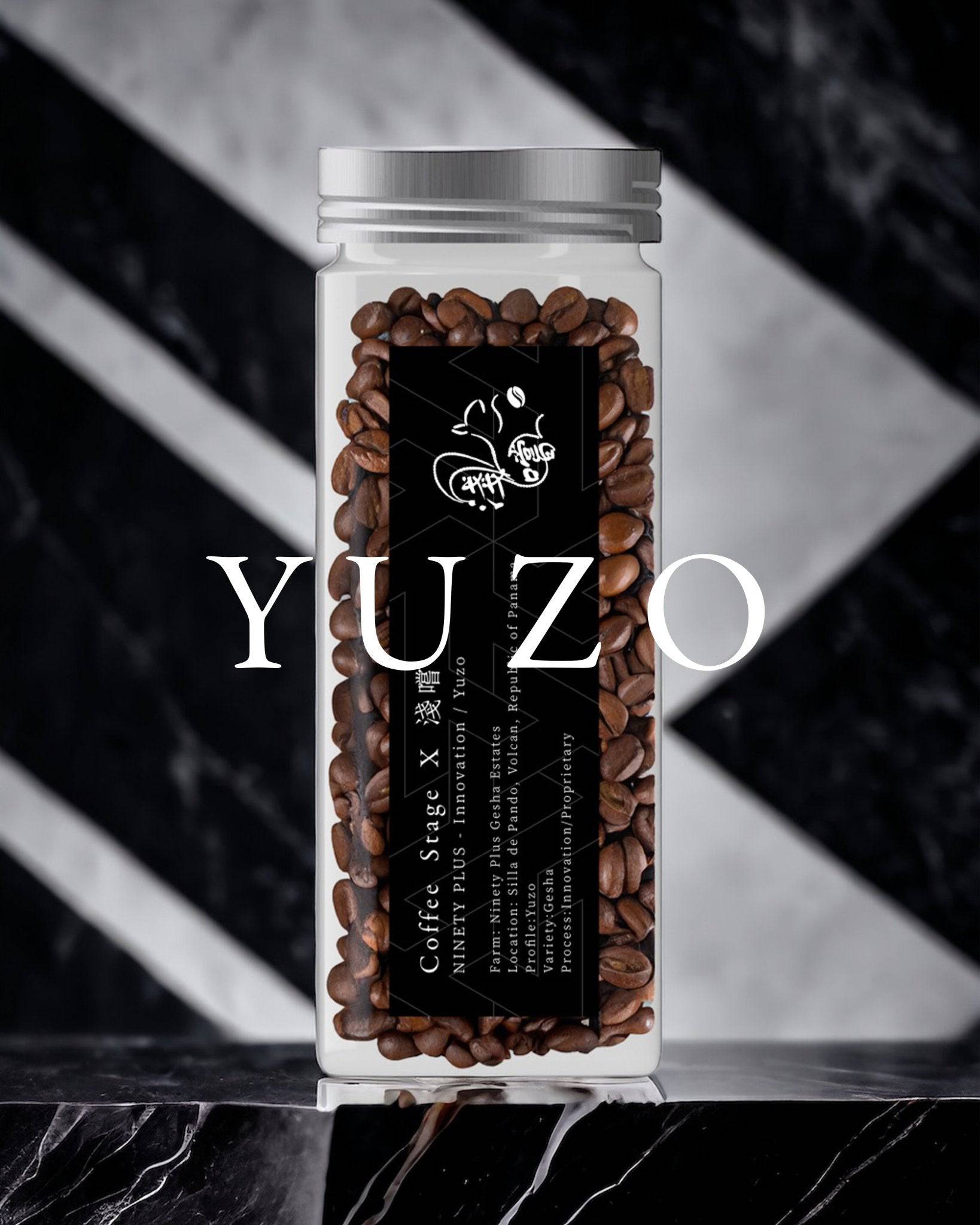 Glass jar filled with premium Ninety Plus Yuzo coffee beans, featuring a black label with white text and logo, set against a dramatic marble and striped background. The word "YUZO" is prominently displayed in white text below the jar.